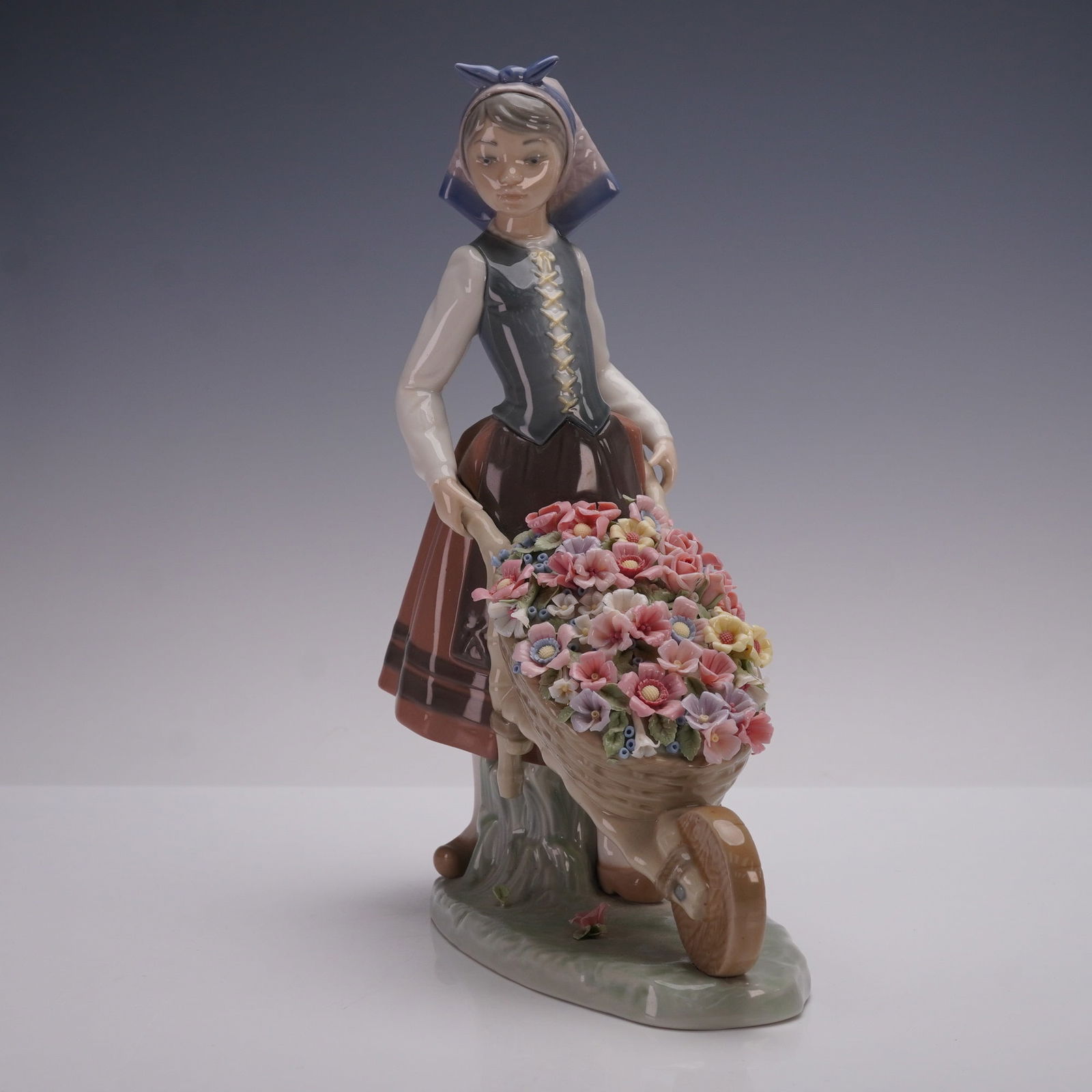 Lladro Porcelain Figurine, A Barrow of Blossoms 01001419: Lladro porcelain figurine 01001419, titled A Barrow of Blossoms, sculpted by Francisco Catala. Issued in 1982 and retired in 2004, this glazed figurine depicts a young woman in traditional attire guid