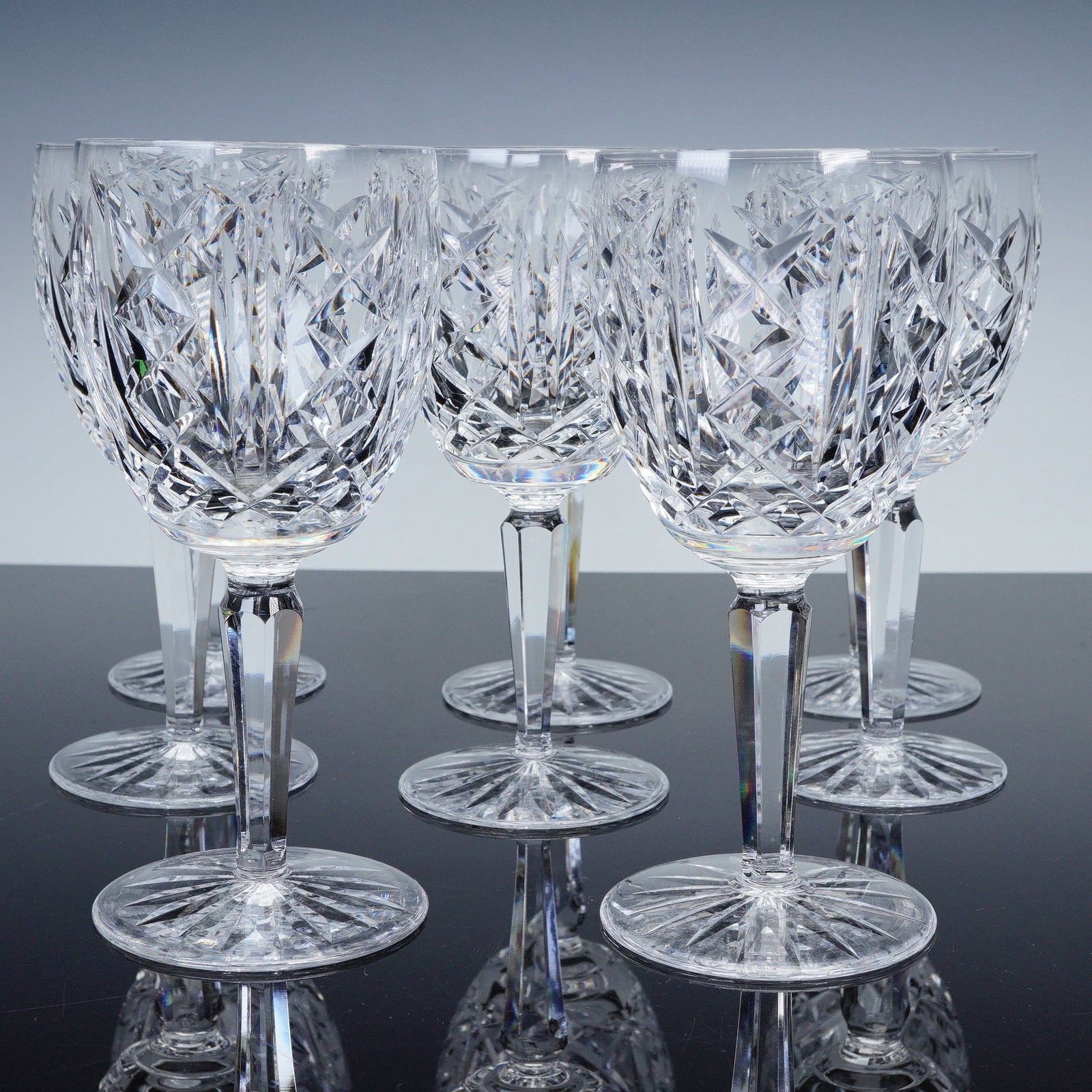 8pc Waterford Glengarriff Crystal Claret Wine Glasses: Each glass features a faceted stem rising to a wide bowl adorned with intricate crosshatched and diamond cut patterns, showcasing Waterford's classic craftsmanship. The bases are star-cut, adding bril