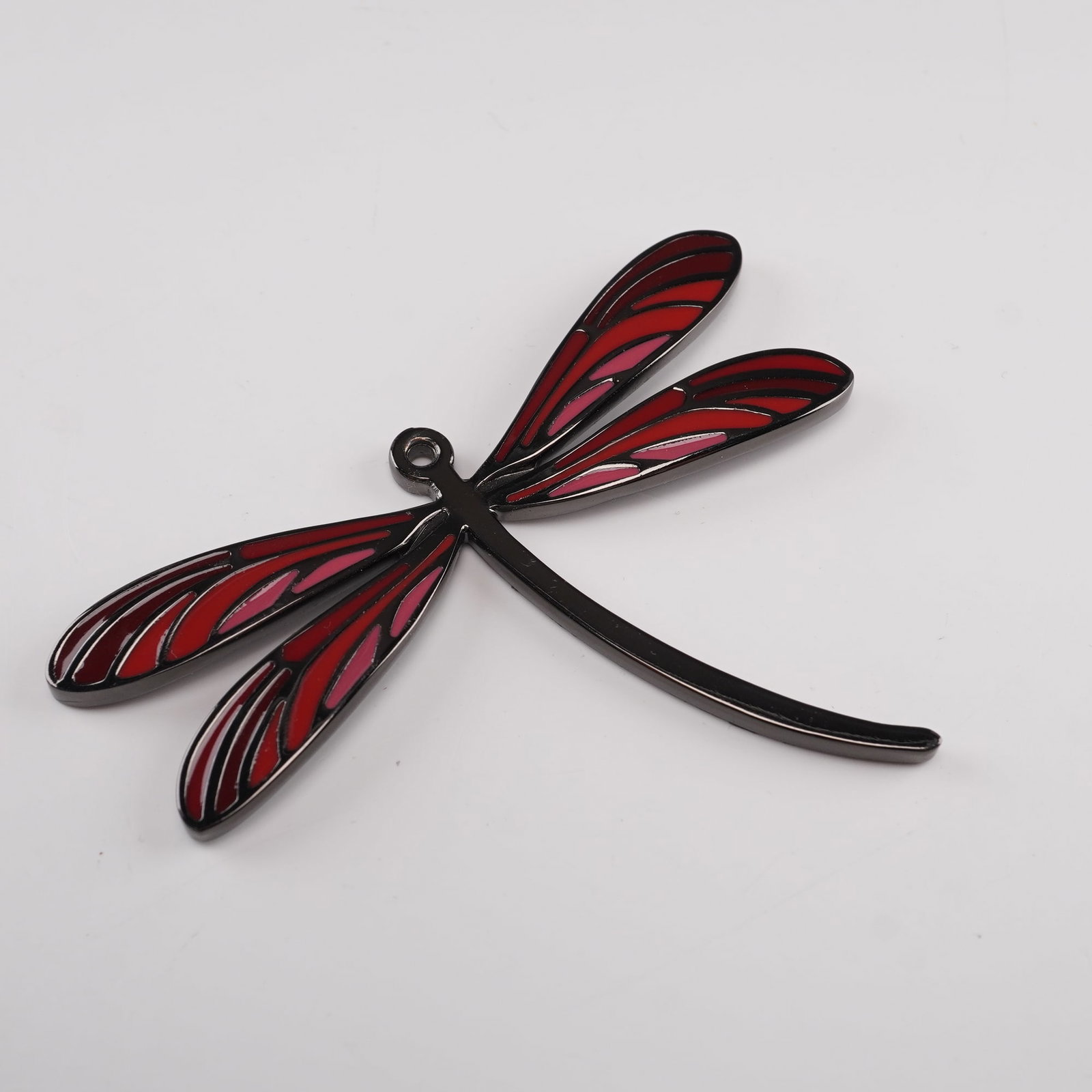 Lalique Metal Dragonfly Pendant with Red and Pink Enamel Wings: This metal dragonfly pendant features a stylized openwork design with vibrant red and pink enamel detailing on the wings, giving it a stained-glass effect. The pendant's bold color palette and smooth 
