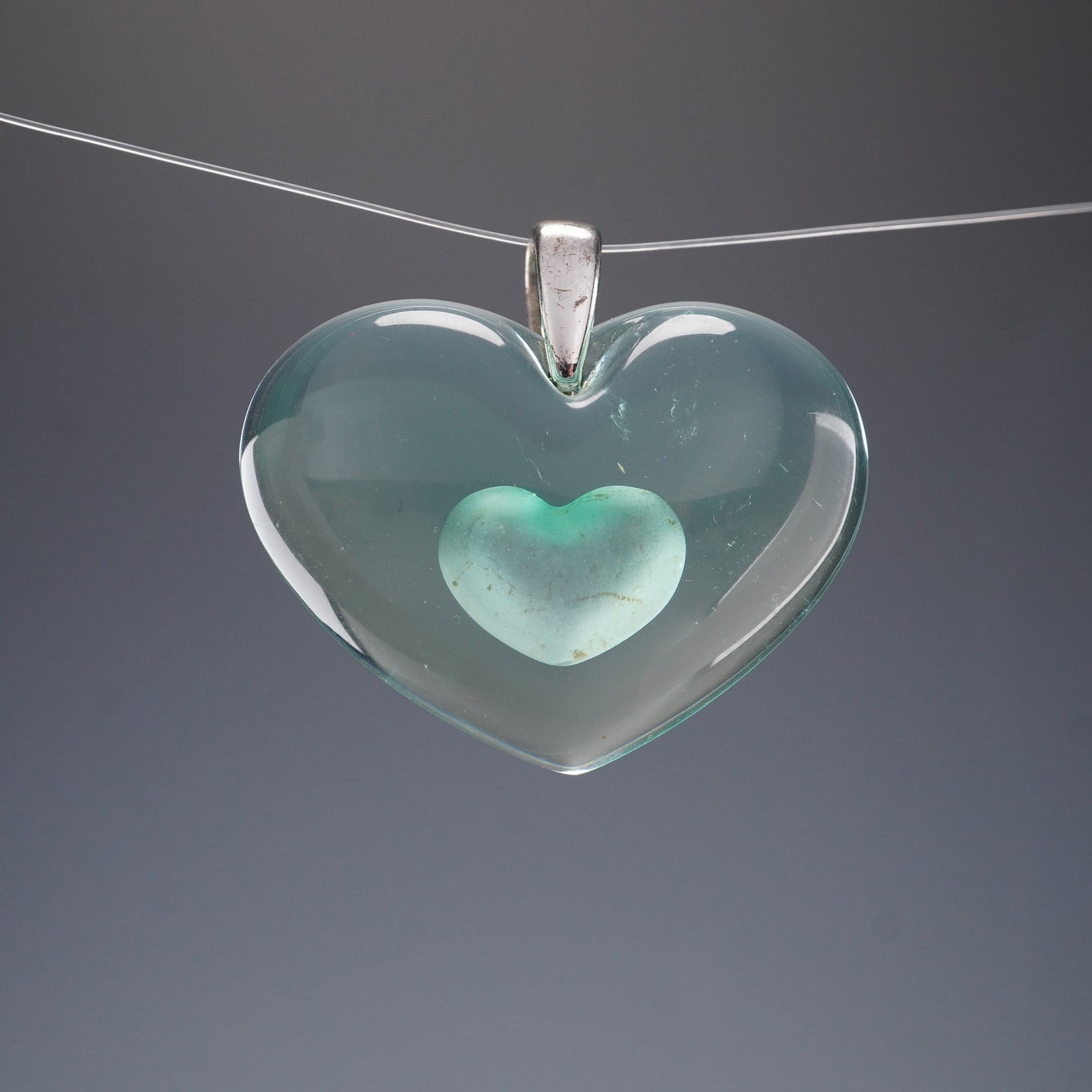 Lalique Tendre Heart Pendant Scents of Delight Crystal Jewelry: The Lalique Tendre Heart Pendant from the Scents of Delight collection features a smooth, translucent crystal heart with a softly frosted heart form suspended at its center, creating a layered and rom