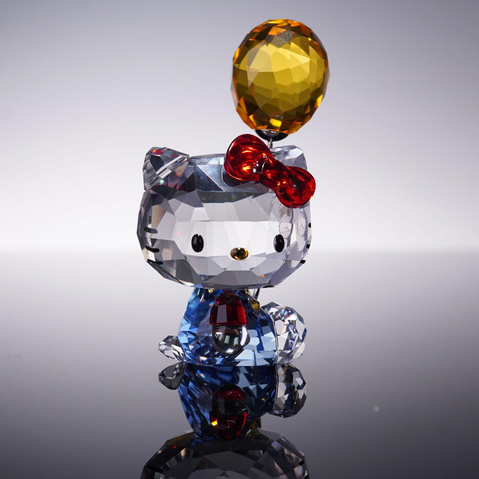 Swarovski Crystal Figurine, Hello Kitty Balloon: One of a kind crystal figurine of Hello Kitty holding a vibrant balloon, exquisitely faceted in clear crystal with accent details. The piece features Hello Kitty adorned with her signature red bow, co
