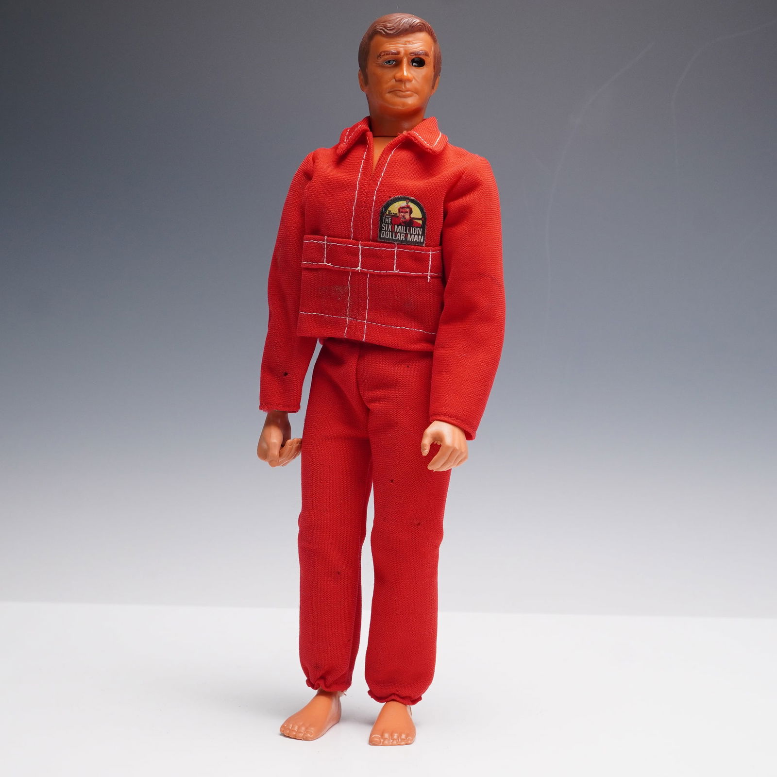 Kenner Six Million Dollar Man, The Bionic Man: Kenner action figure of Steve Austin from The Six Million Dollar Man television series. The figure is dressed in its original red tracksuit with logo patch on the chest and features the trademark bion