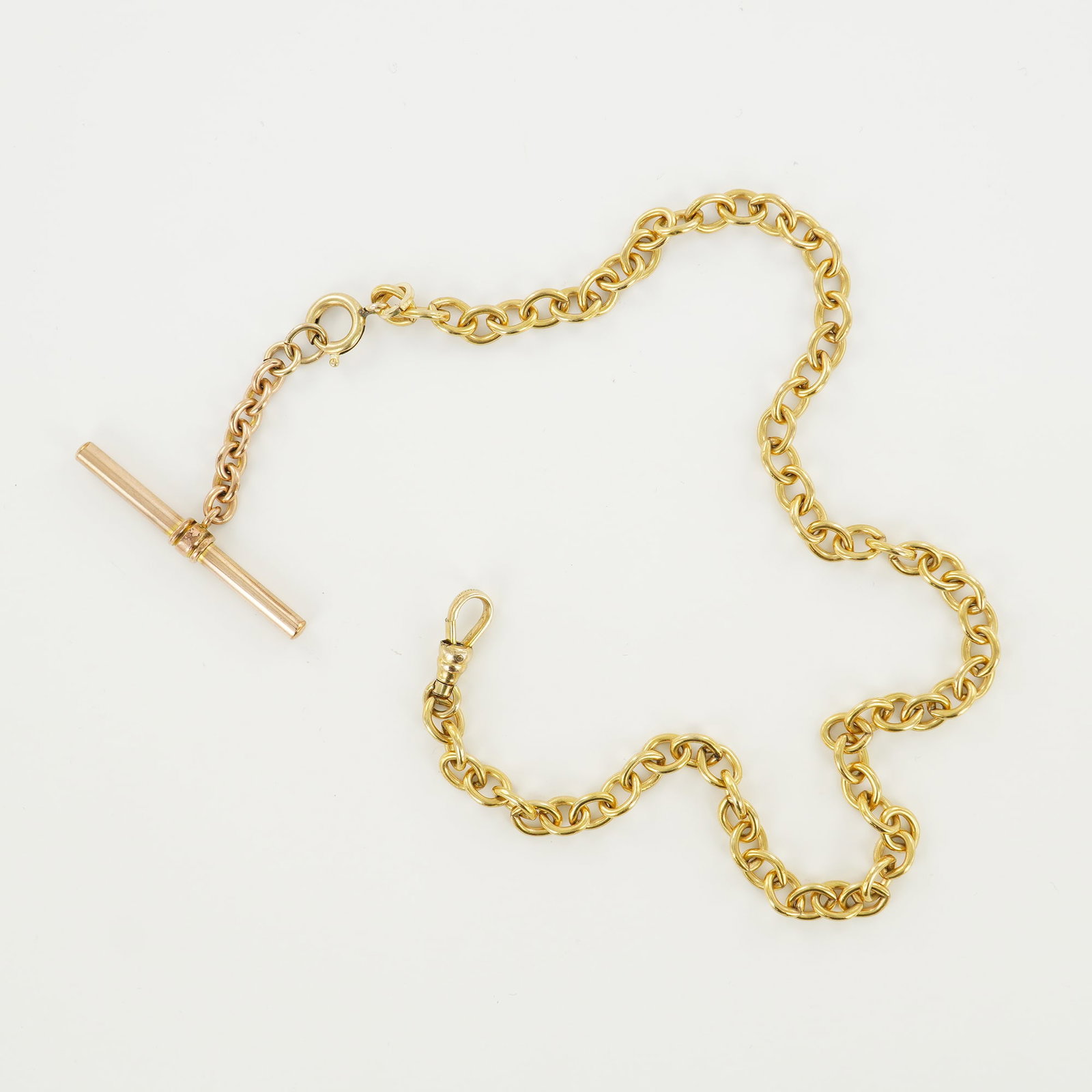 Gold T-Bar Fob Pocket Watch Chain: Gold T-Bar Fob Pocket Watch Chain composed of interlocking circular links, terminating at one end with a T-bar fob and at the other with a swivel clasp. The T-bar is attached via a short length of cha