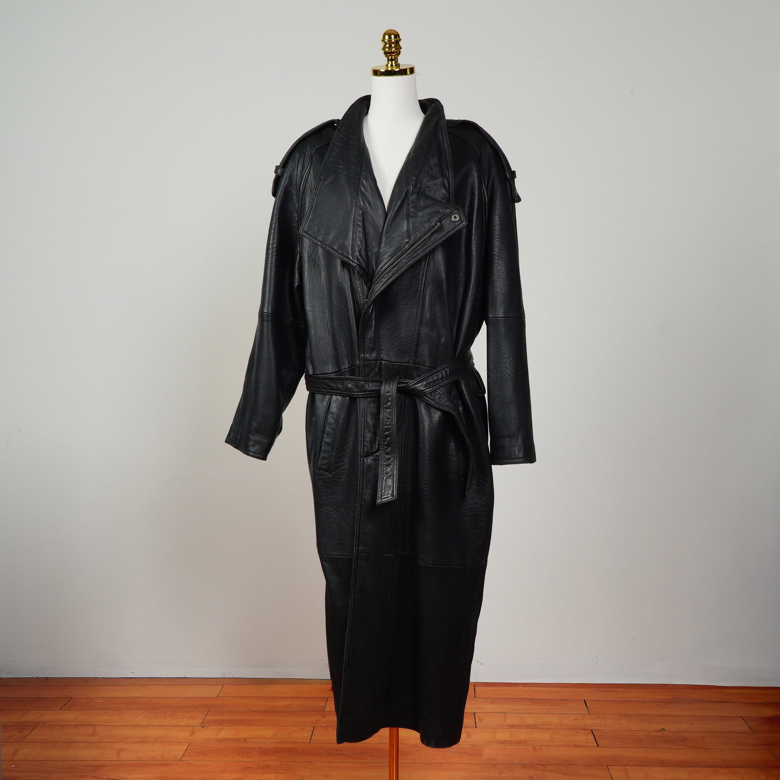Black IOU Leather Trench Coat with Belt: A striking black leather trench coat from the IOU Leather Collection, crafted in a bold oversized silhouette. This dramatic full-length coat for men features wide notched lapels, epaulets at the shoul