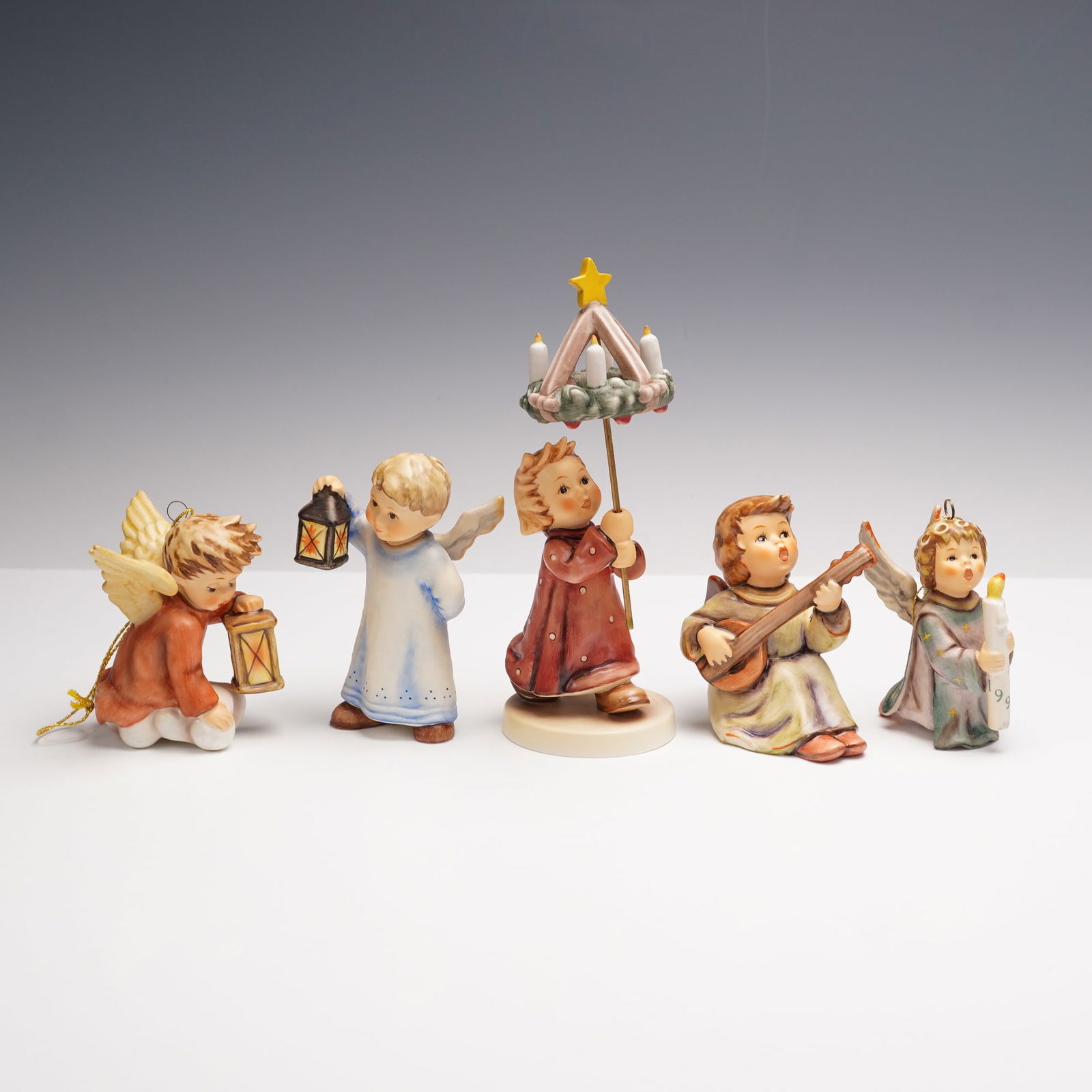 5pc Goebel Hummel Figurines and Ornaments, Christmas Angels: A joyful gathering of five Goebel Hummel angels, each one capturing the innocence and magic of the holiday season. This group includes the 1991 Angel ornament holding a glowing candle, the 1992 Angel