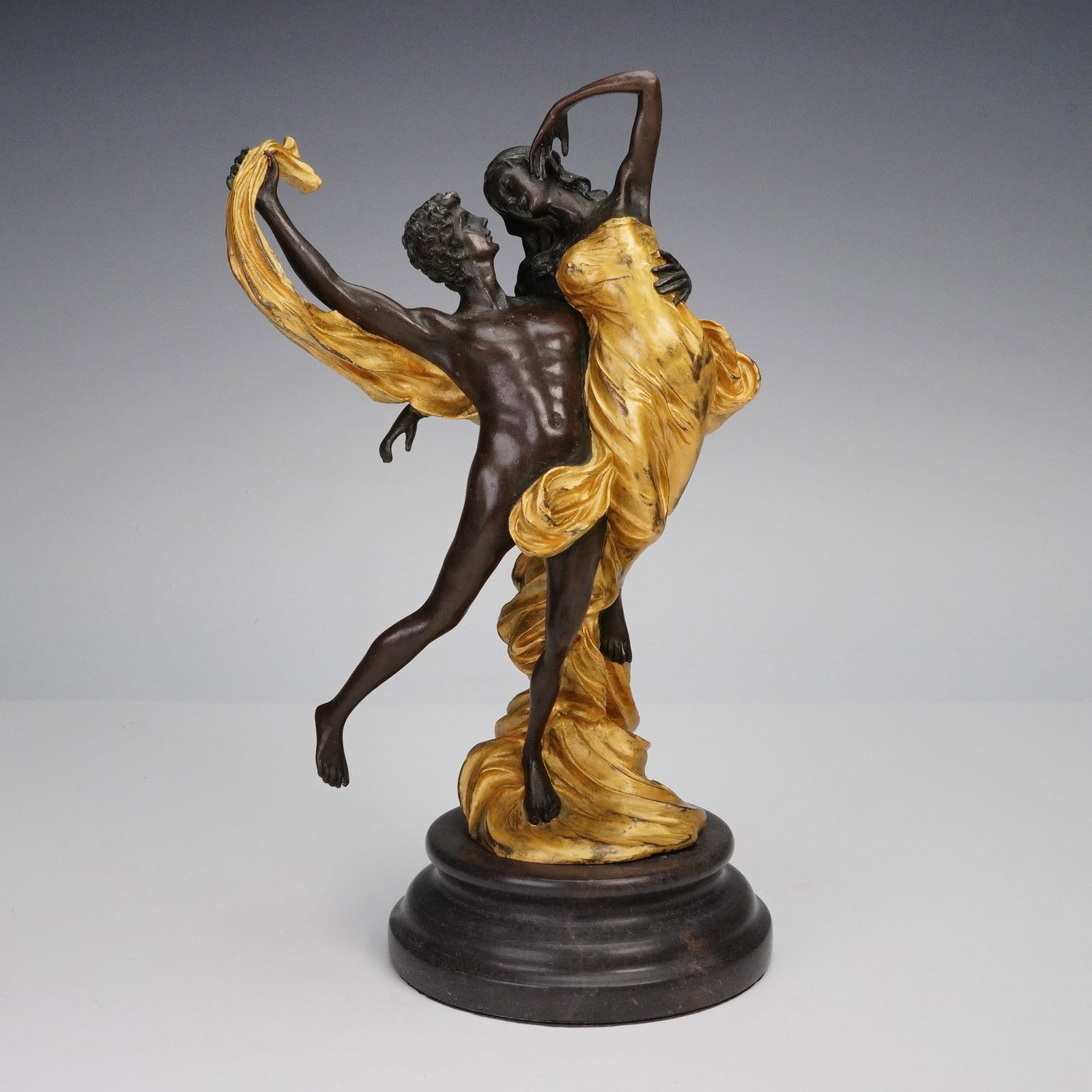 Jean Didier Debut Bronze Sculpture, Lover's Embrace: Figural bronze sculpture depicting a couple in a passionate dance, the male figure lifting the female as she leans gracefully back, both entwined in flowing drapery finished in a rich golden hue. Cast