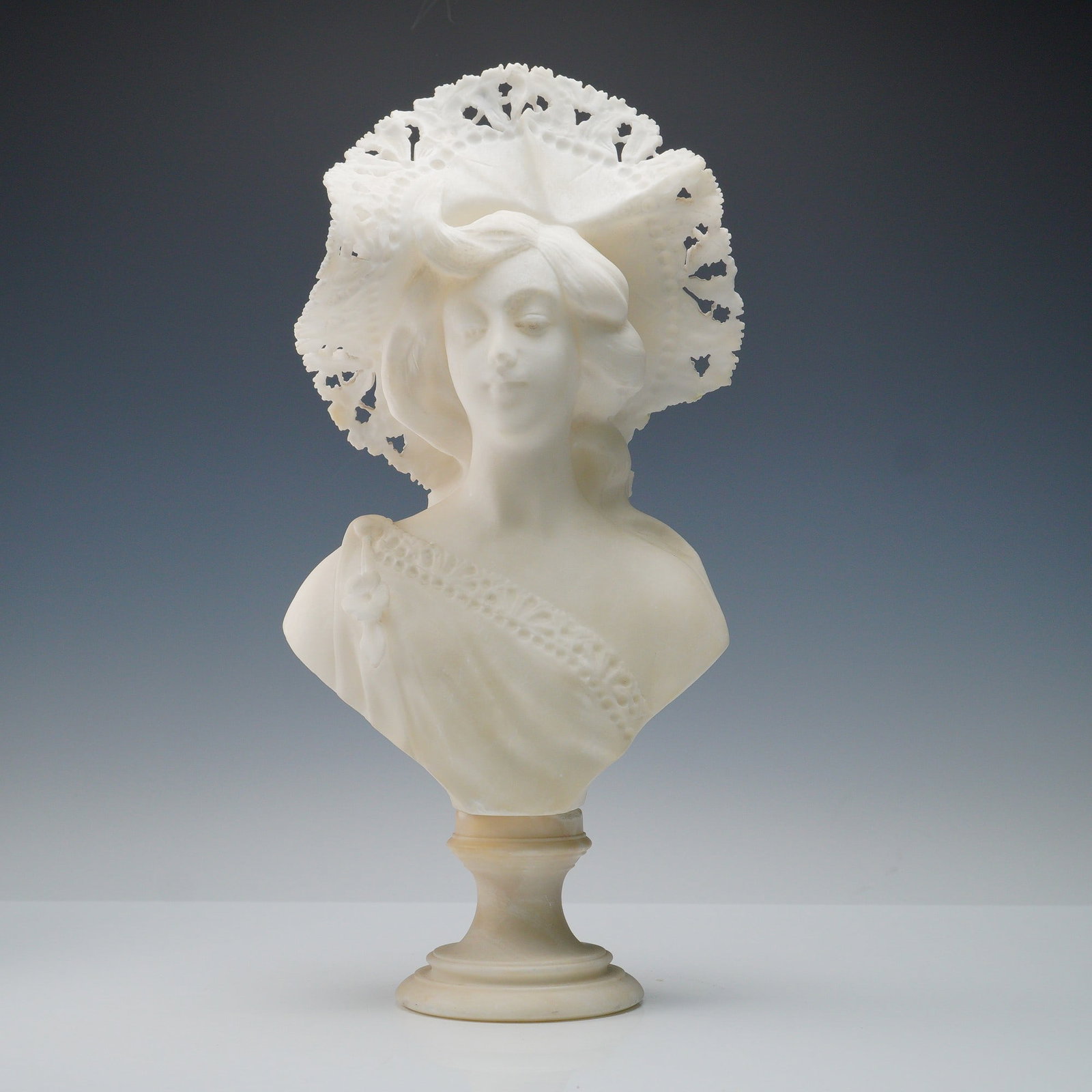Alabaster Bust of a Lady with Pierced Bonnet: Delicately rendered alabaster bust portraying a lady in a wide, pierced lace bonnet, her features softly modeled with a calm, poised expression. The artist's skill is evident in the intricate openwork