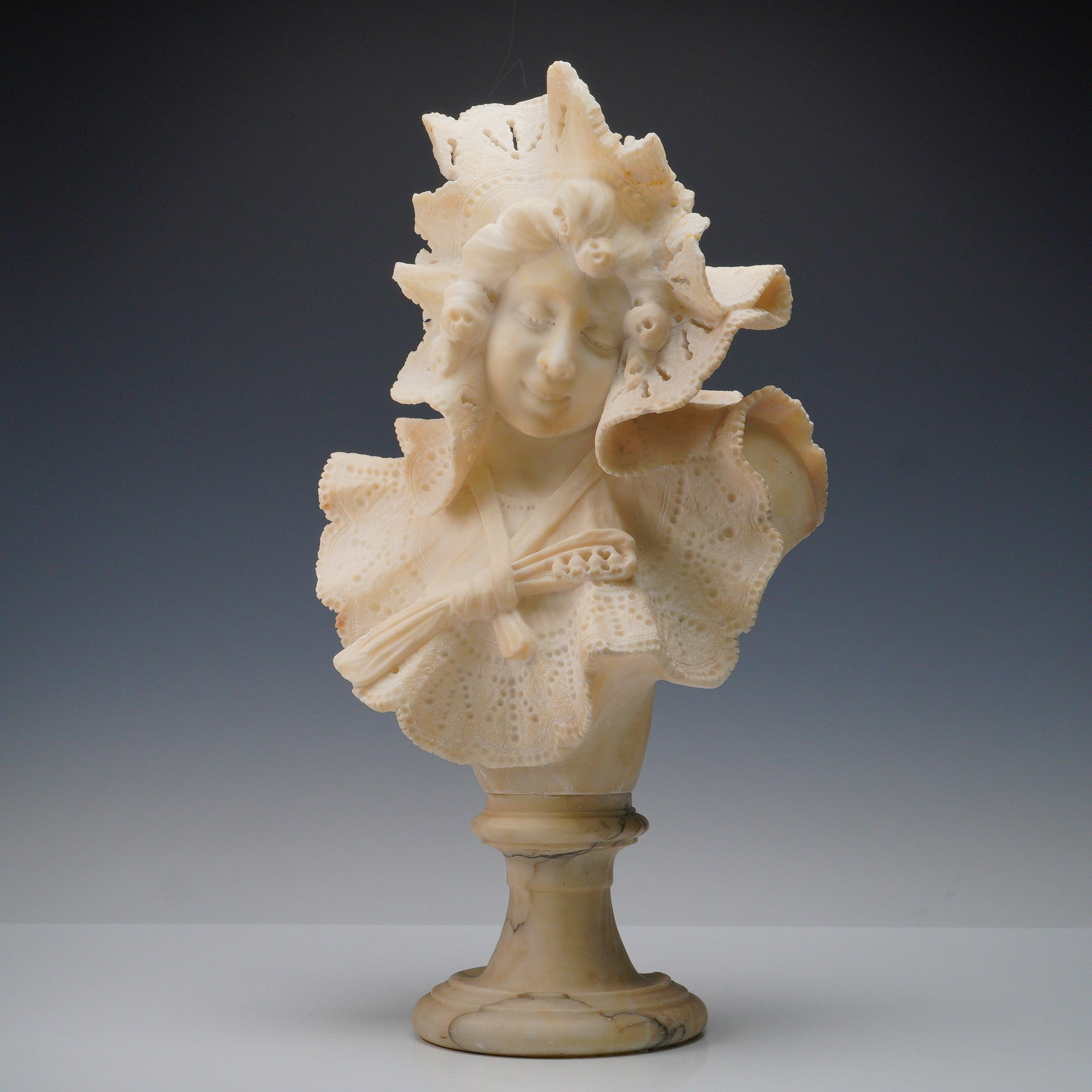 Alabaster Bust of a Woman in Lace Bonnet: Finely detailed carved alabaster bust depicting a serene woman with downcast gaze, adorned in a lace bonnet and shawl. The intricate pierced lacework and delicate facial features showcase exceptional 