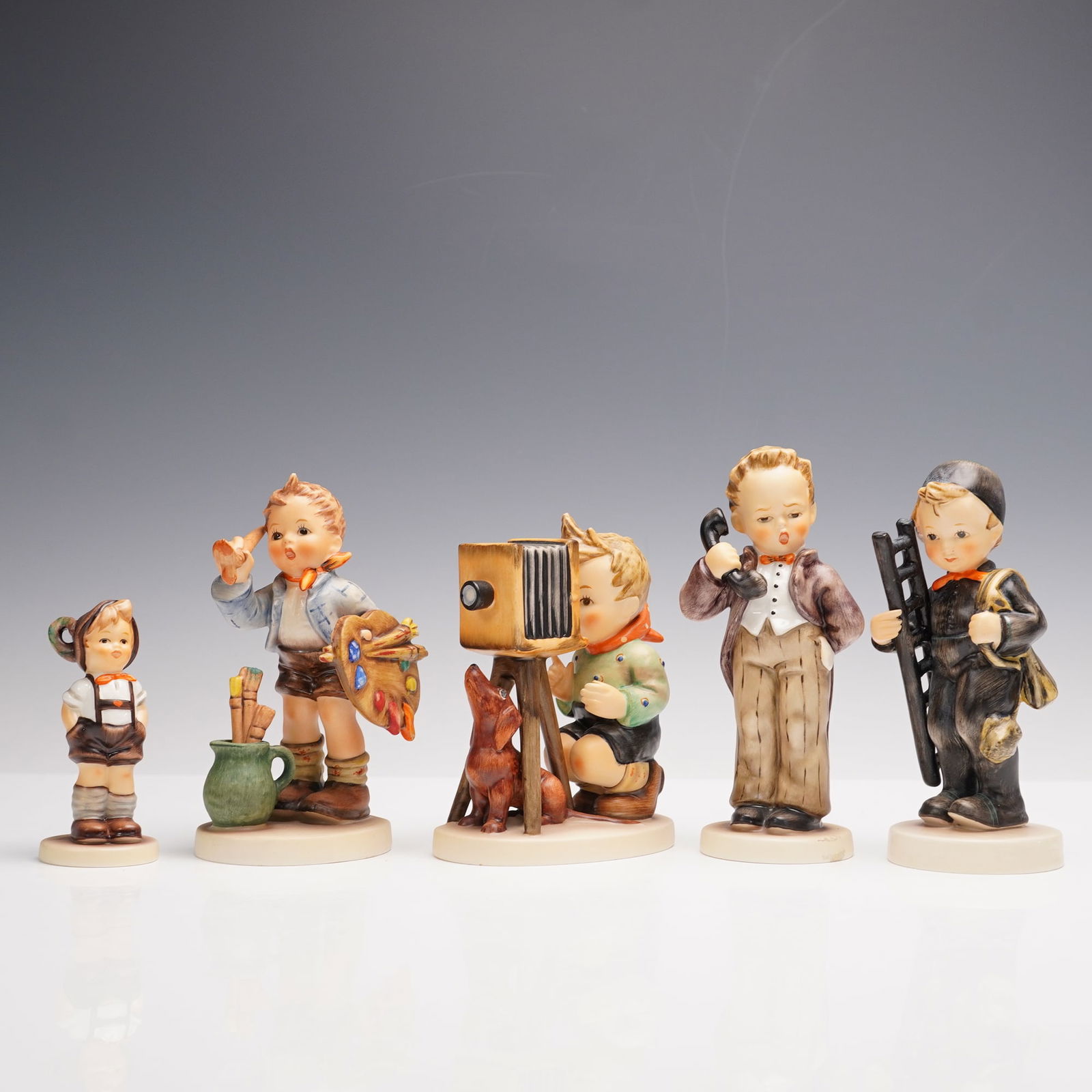 5pc Goebel Hummel Figurines, Professions: A whimsical lineup of Goebel Hummel figurines celebrating the world of childhood imagination and grown-up professions. This set includes Hello Chef 1240, a little culinary dreamer standing proudly in