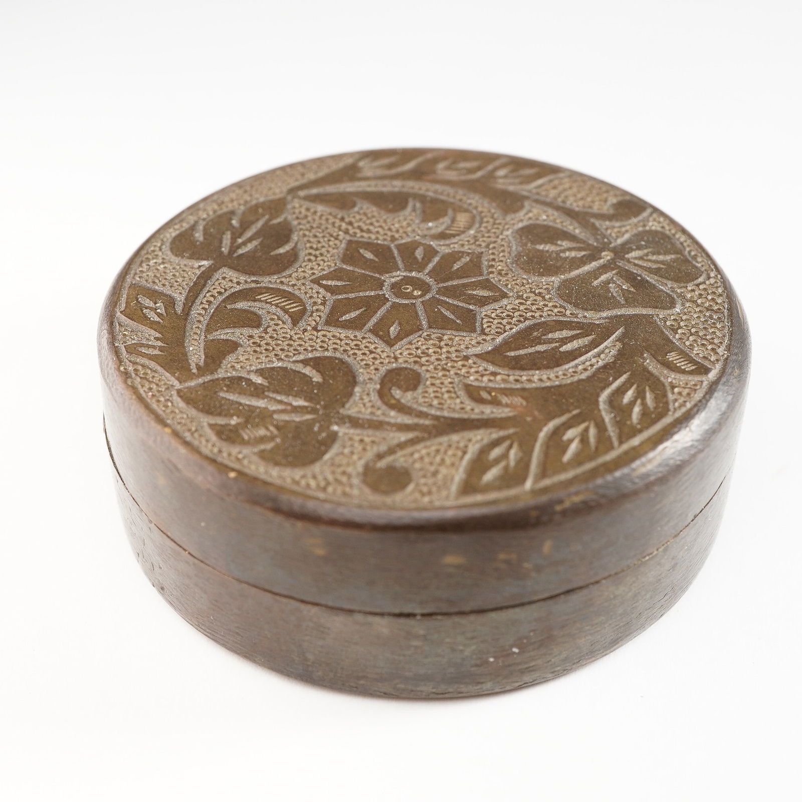 Afghanistan Brass Cylindrical Box: This antique cylindrical box is crafted from brass with an intricate design. The box features a floral motif engraved across the top lid, showcasing traditional craftsmanship and artistic details char