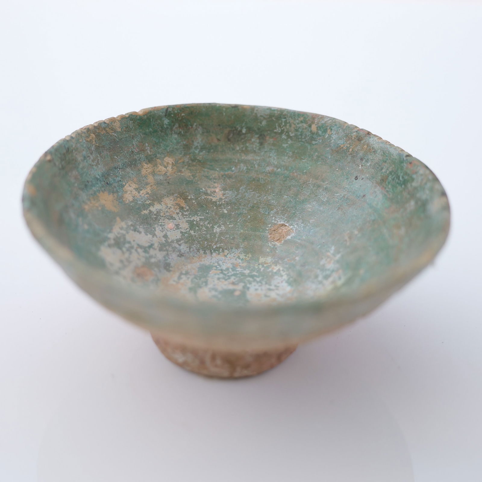 Islamic Persian Kashan Ceramic Bowl: A shallow stoneware bowl raised on a narrow, cylindrical foot. The bowl exhibits a broad, rounded rim and inward-sloping walls, with visible turning lines along both the interior and exterior surfaces
