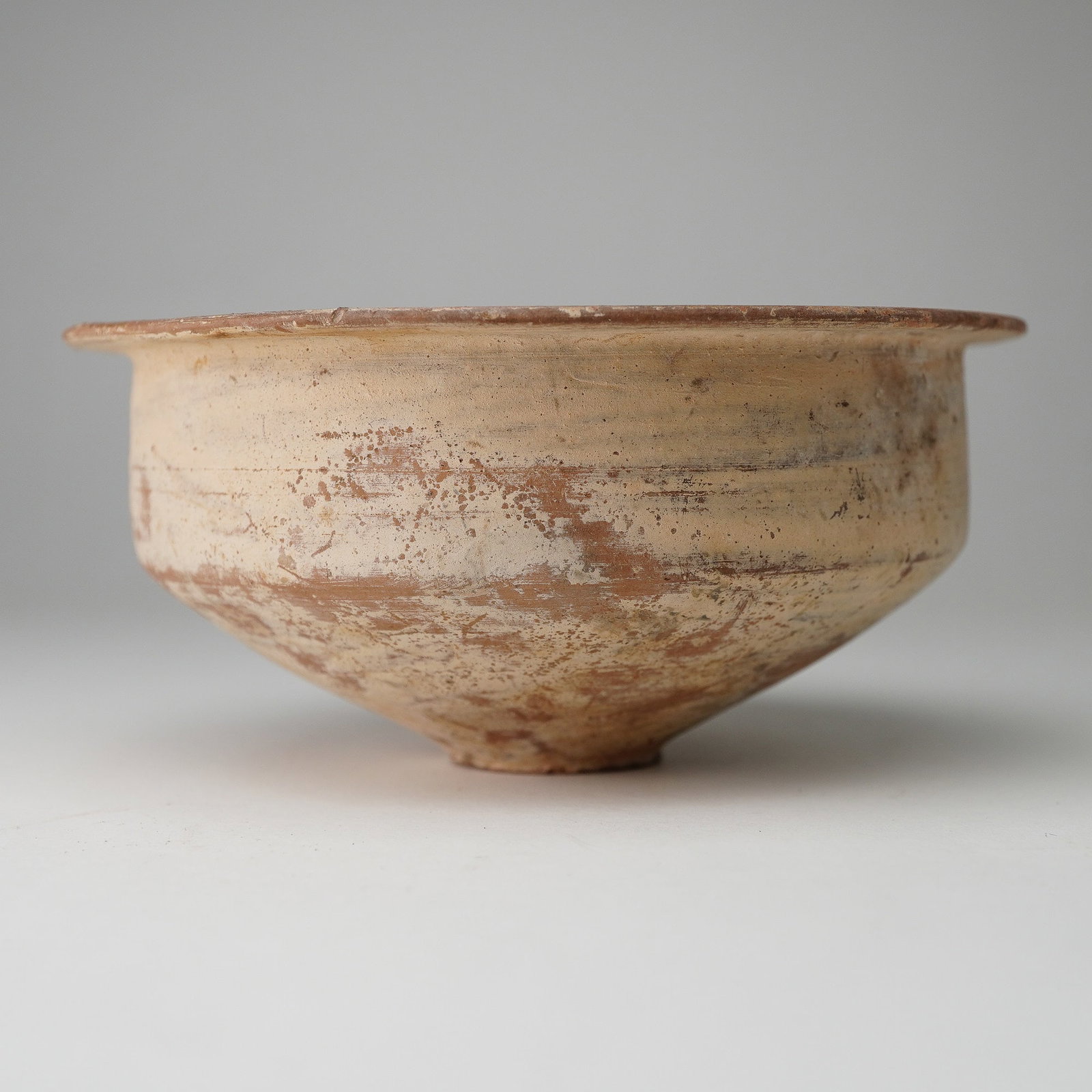 Small Pre-Columbian Terracotta Bowl: This antique small terracotta bowl features a conical shape with a flared rim and a narrow foot, crafted from natural clay. The bowl's surface showcases earthy hues with varying tones of reddish-brown