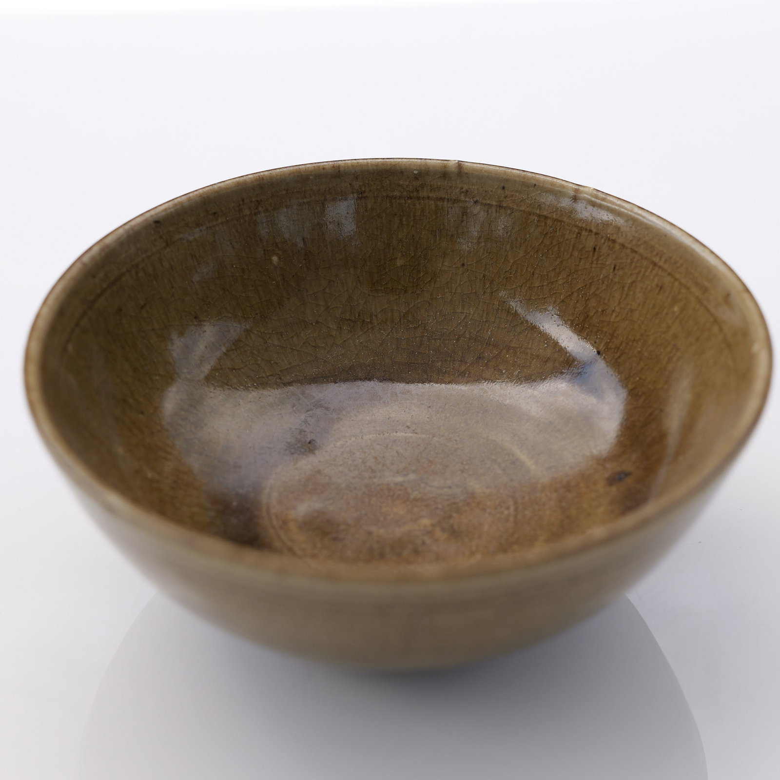 Chinese Celadon Ceramic Lotus Bowl: Featuring a faint lotus motif incised at the center of the interior base. The interior surface is finished with a glossy greenish-brown glaze exhibiting subtle tonal variations and natural glaze pooli