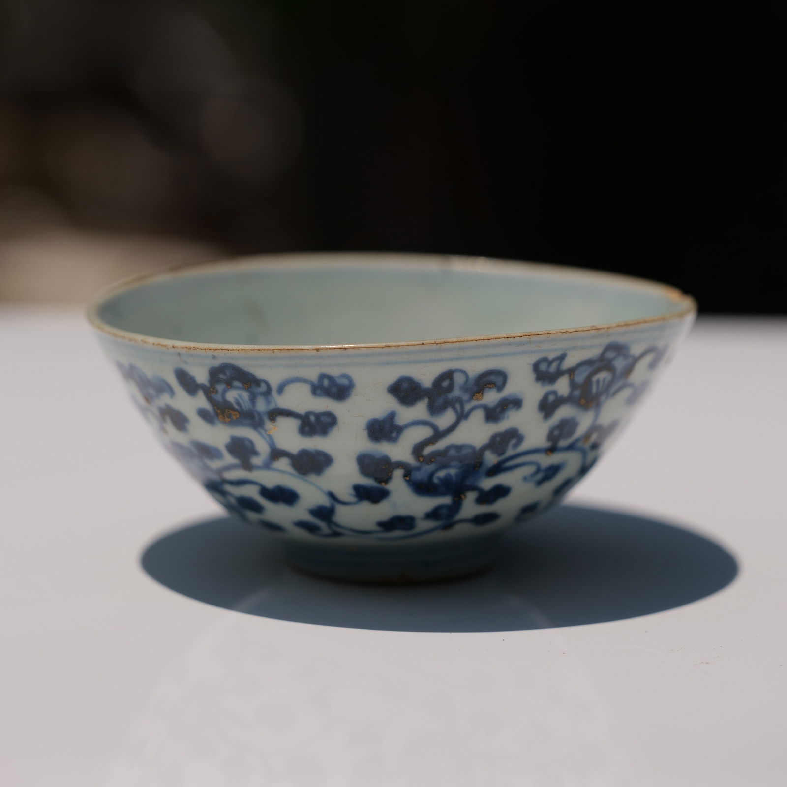 Chinese Blue and Gild Floral Bowl: This antique Chinese porcelain bowl is decorated with underglaze cobalt blue floral motifs, accented by traces of applied gilt detailing. The exterior features a repeating pattern of scrolling floral