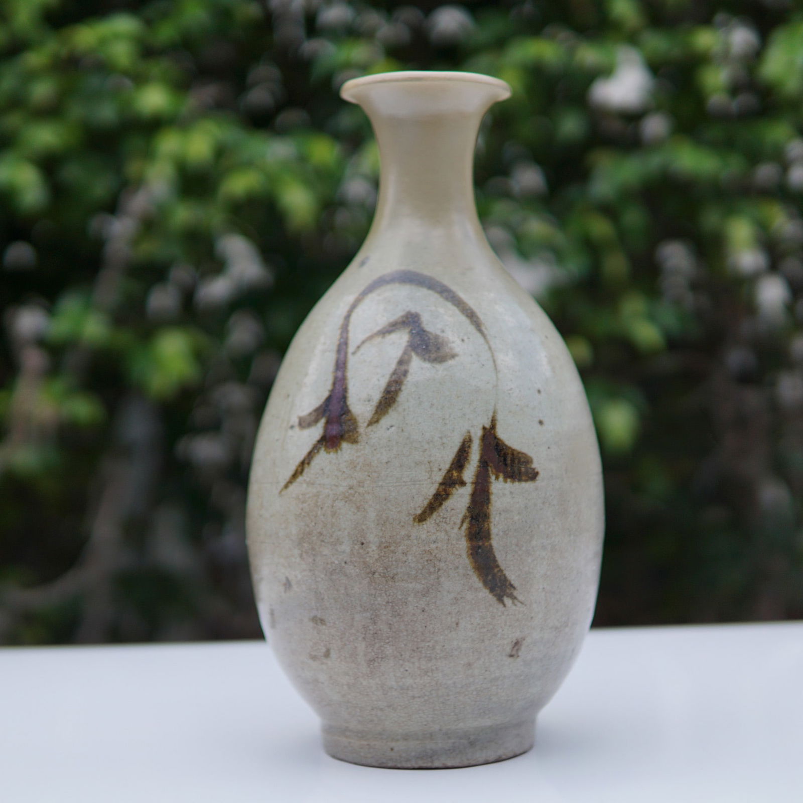 Asian Iron-Decorated Stoneware Vase: Stoneware vase featuring a bulbous ovoid body tapering slightly to a recessed foot and rising into a tall neck with a wide flared mouth. The surface is finished in a gray glaze with dense crazing and