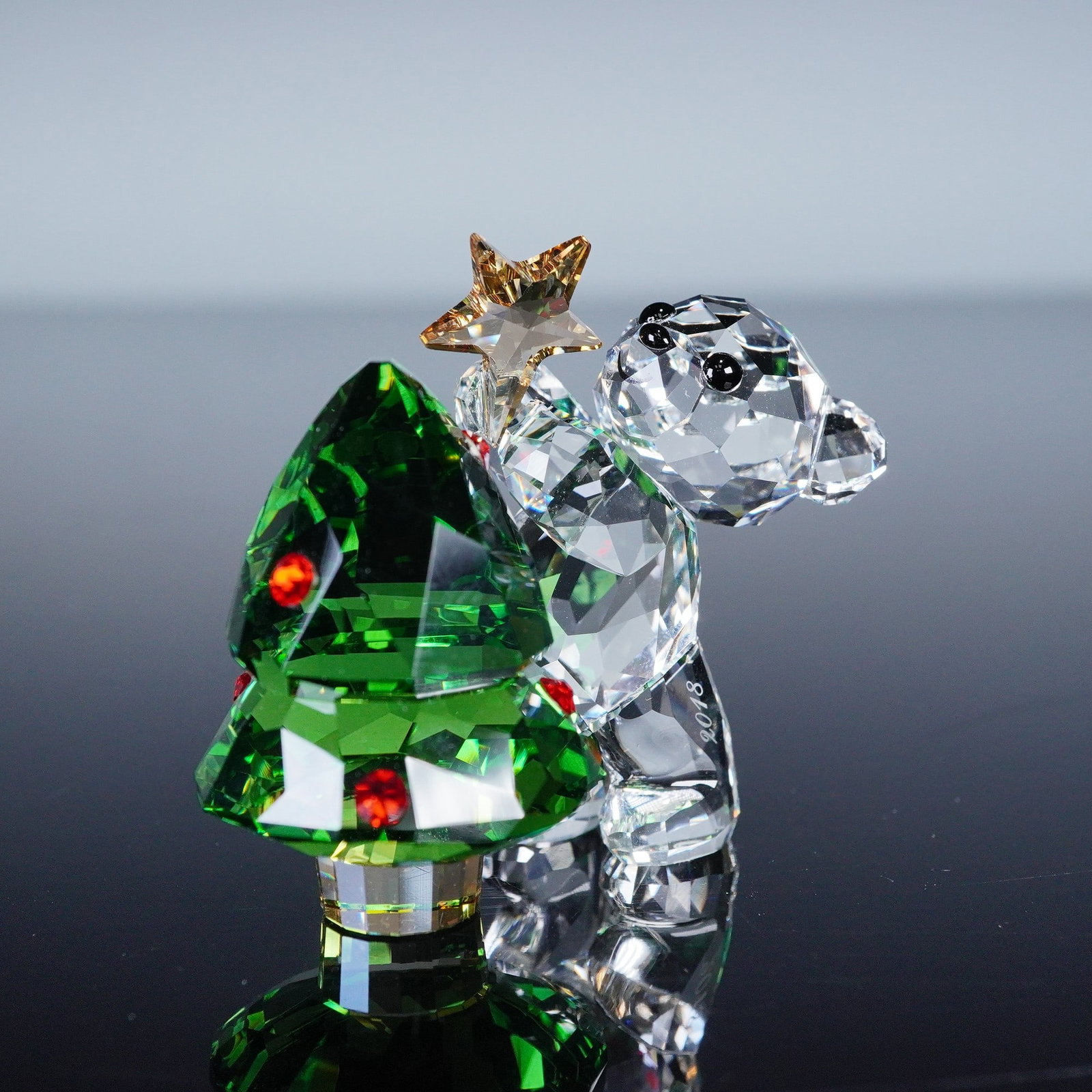 Swarovski Lovlots Crystal 2018 Kris Bear Figurine, Decorating Christmas Tre: Issued as the Annual Edition for 2018 to commemorate the 25th anniversary of the Kris Bear line first introduced in 1993. The figurine depicts a faceted clear crystal Kris Bear in an active pose, hold