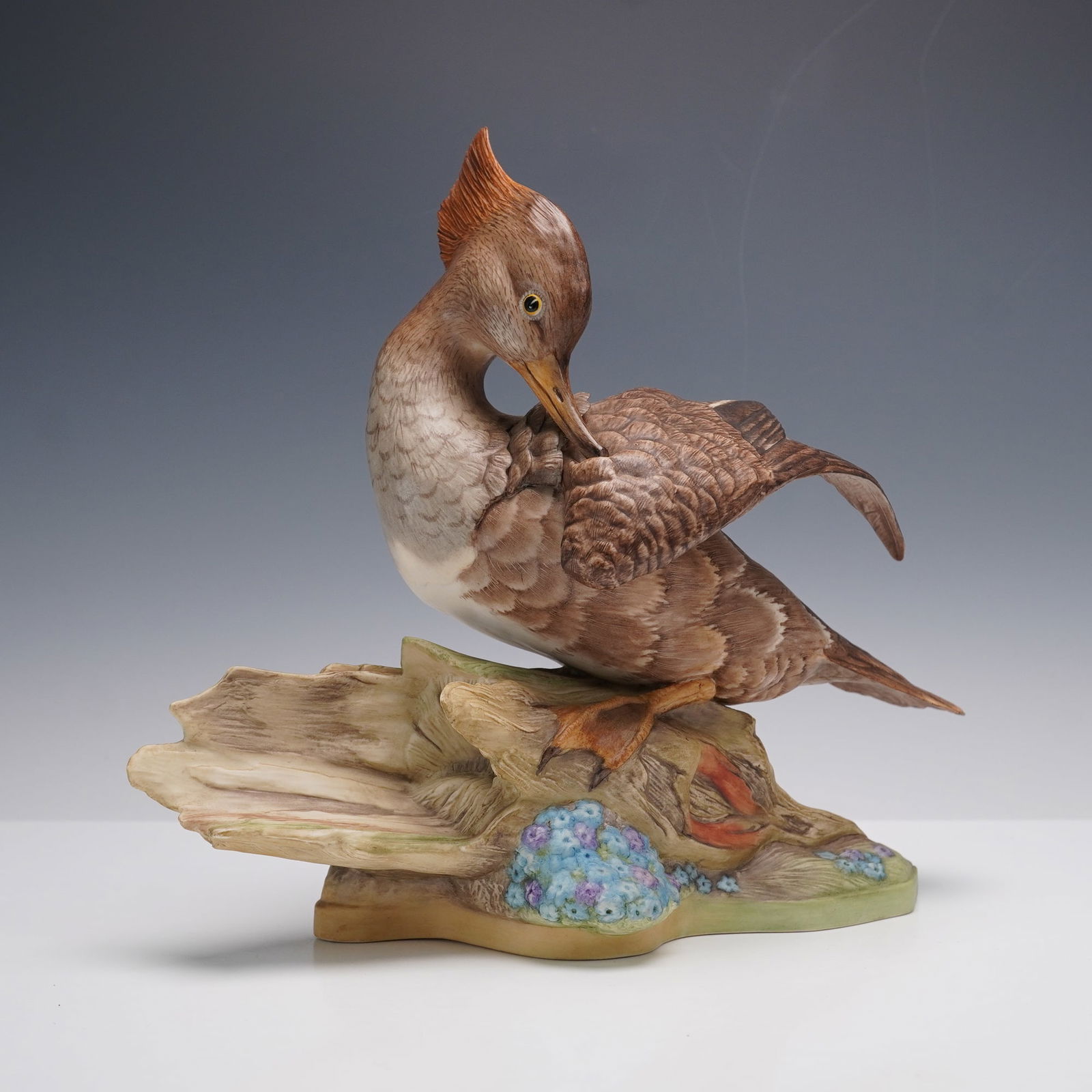 Boehm Porcelain Figurine, Hooded Merganser 496: Produced in a limited edition. The hand-painted sculpture depicts a detailed female hooded merganser perched on a naturalistic base with driftwood and foliage. This finely modeled work displays the di