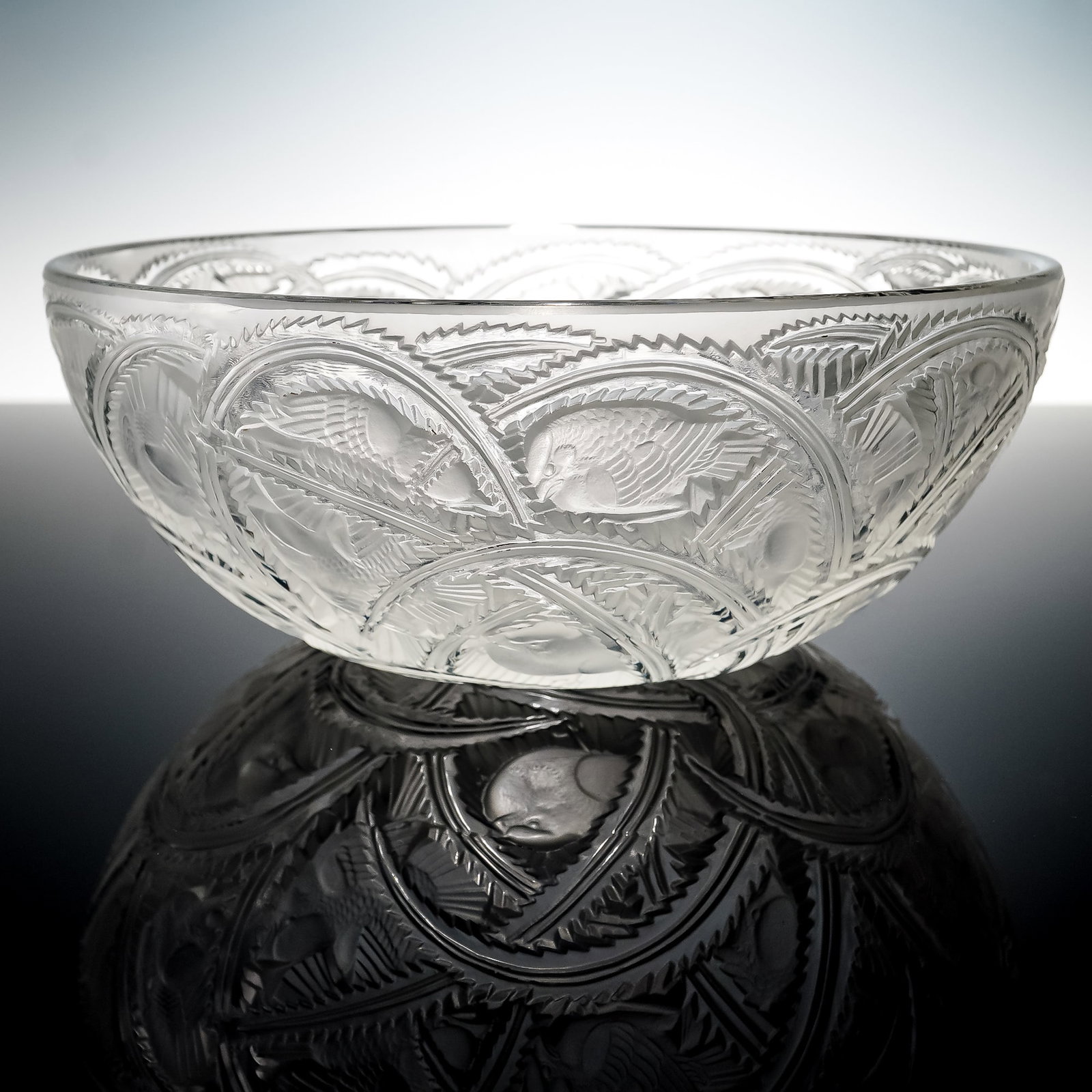 Lalique France Crystal Bowl, Pinsons: A Lalique France crystal bowl with frosted and clear finish featuring relief decoration of birds and foliage in repeating circular panels. Signed Lalique France to the base. Issued: 20th century Dimen