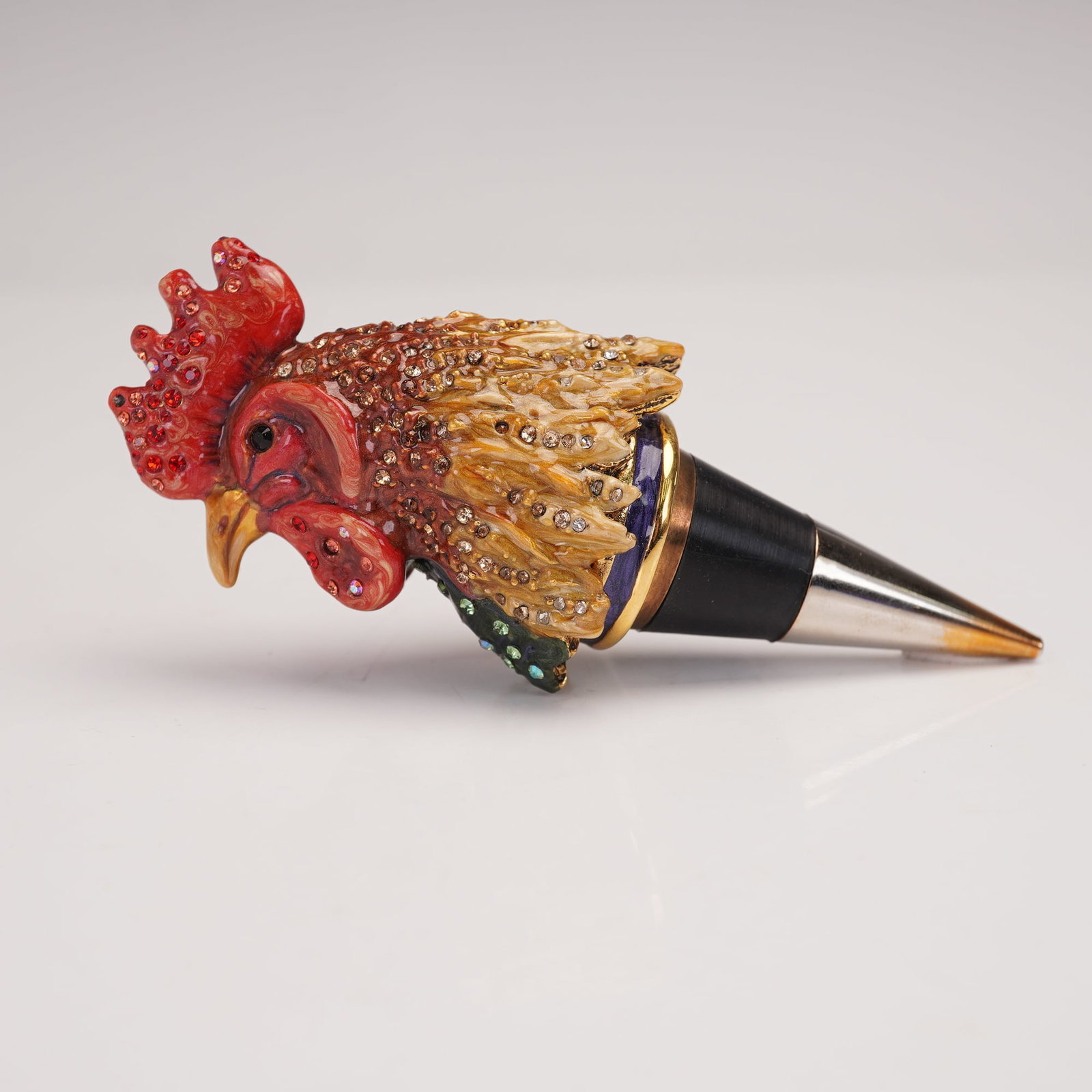 Jay Strongwater Bejeweled Rooster Bottle Stopper: Featuring a finely crafted rooster head adorned with multicolored enamel and sparkling crystal accents. The sculpted form displays detailed plumage highlighted in shades of red, gold, and green, with 