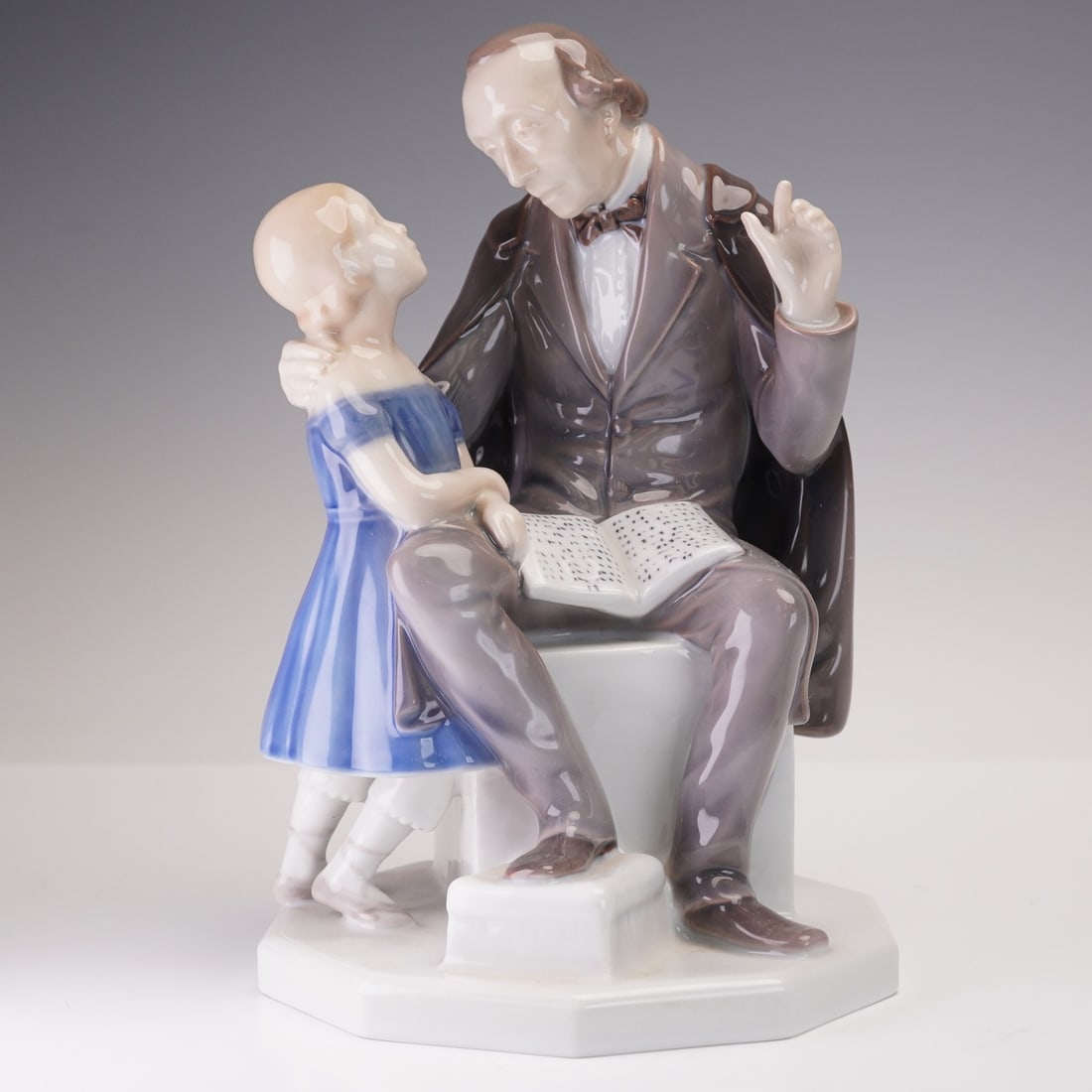 Bing & Grondahl Porcelain Figurine, Hans Christian Andersen: A charming porcelain figurine depicting Hans Christian Andersen, the renowned Danish author, engaged in storytelling with a young girl. This piece captures the gentle moment of narration, with Anderse