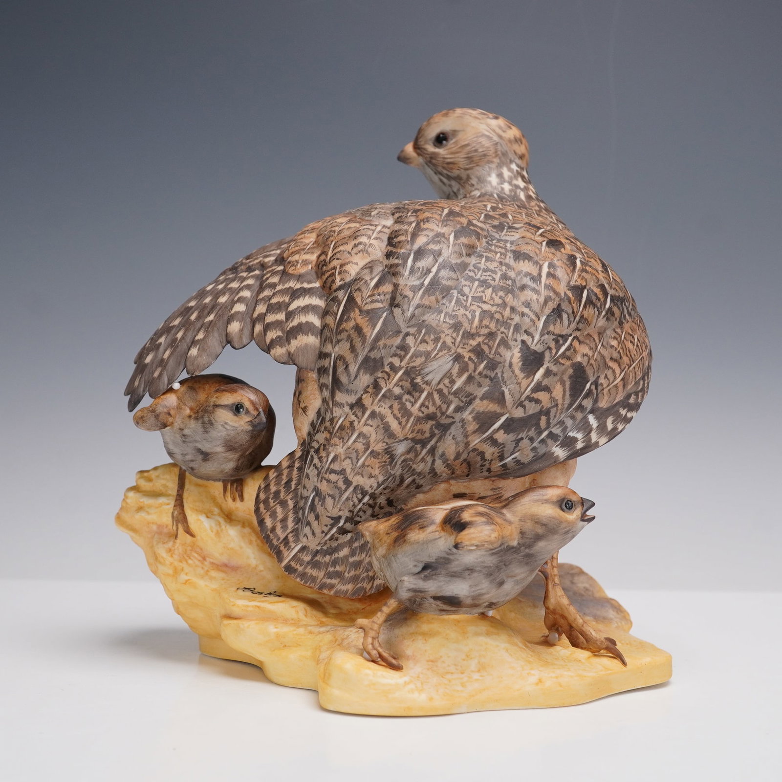 Boehm Porcelain Figurine, Mearns' Quail 467: A finely detailed Boehm porcelain figurine portraying a mother Mearns' quail with two chicks nestled beside her. The naturalistic hand-painted plumage in shades of brown and gray captures the intricat