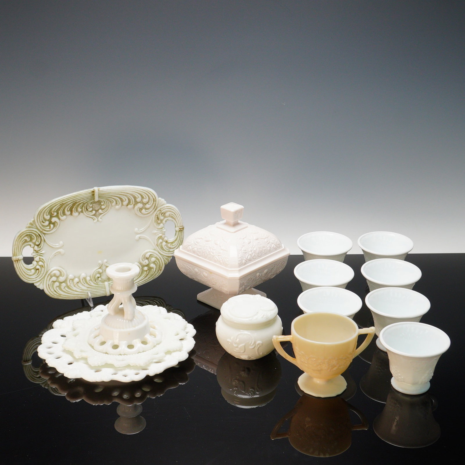 14pc Vintage Milk Glass Tableware: A charming assortment of vintage milk glass tableware, offered in fourteen pieces, each showcasing delicate molded detail and elegant translucent surfaces. The group includes seven footed teacups in t