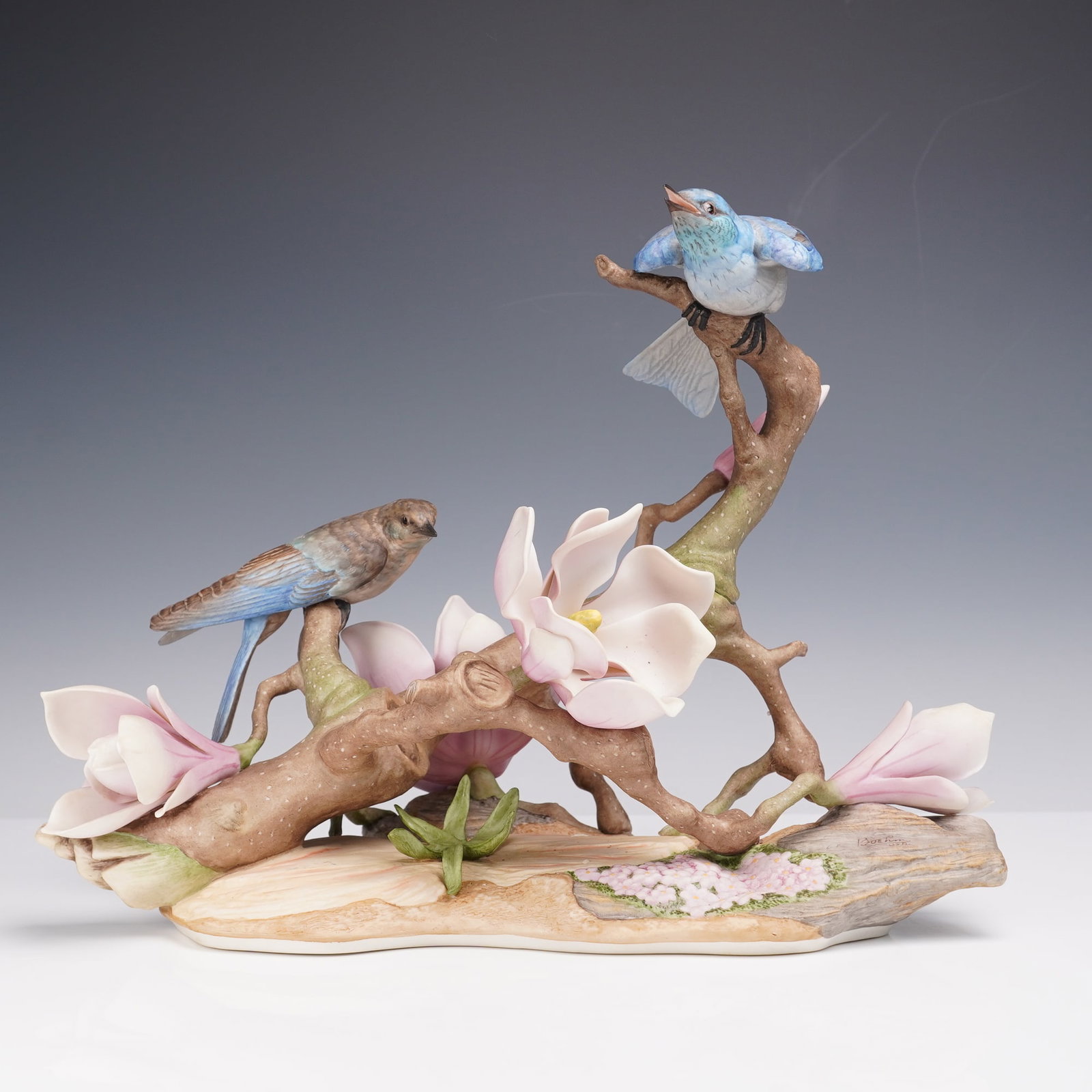 Boehm Porcelain Figurine, Mountain Bluebirds 470: Limited edition. The hand-painted sculpture depicts a pair of detailed bluebirds perched among magnolia blossoms and branches, with a naturalistic base featuring bark and floral textures. Marked 'Boeh