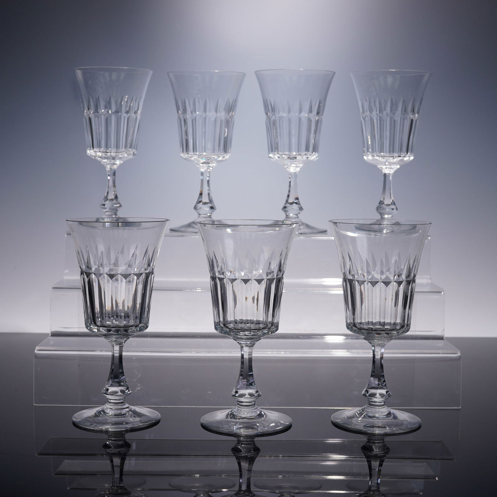 7pc Baccarat Navarre Pattern Water Goblets: A refined set of seven Baccarat crystal water goblets in the Navarre pattern, featuring a flared bowl with vertical and arched cuts rising from a faceted stem. Each piece carries the Baccarat backstam