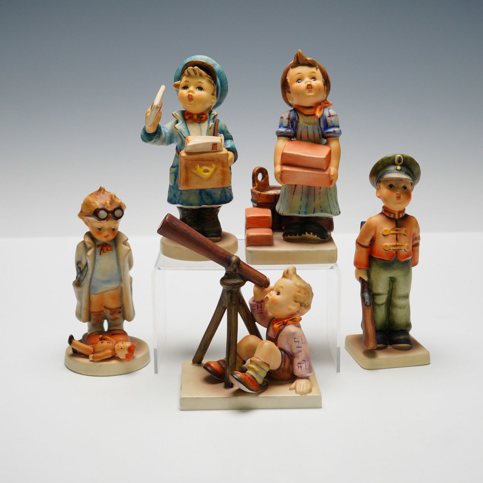 5pc Goebel Hummel Figurines: Collection including "Soldier Boy" (HUM332) depicting a boy in uniform holding a rifle, "Star Gazer" (HUM132) featuring a boy seated with a telescope, "The Postman" (HUM119) showing a boy with a lette