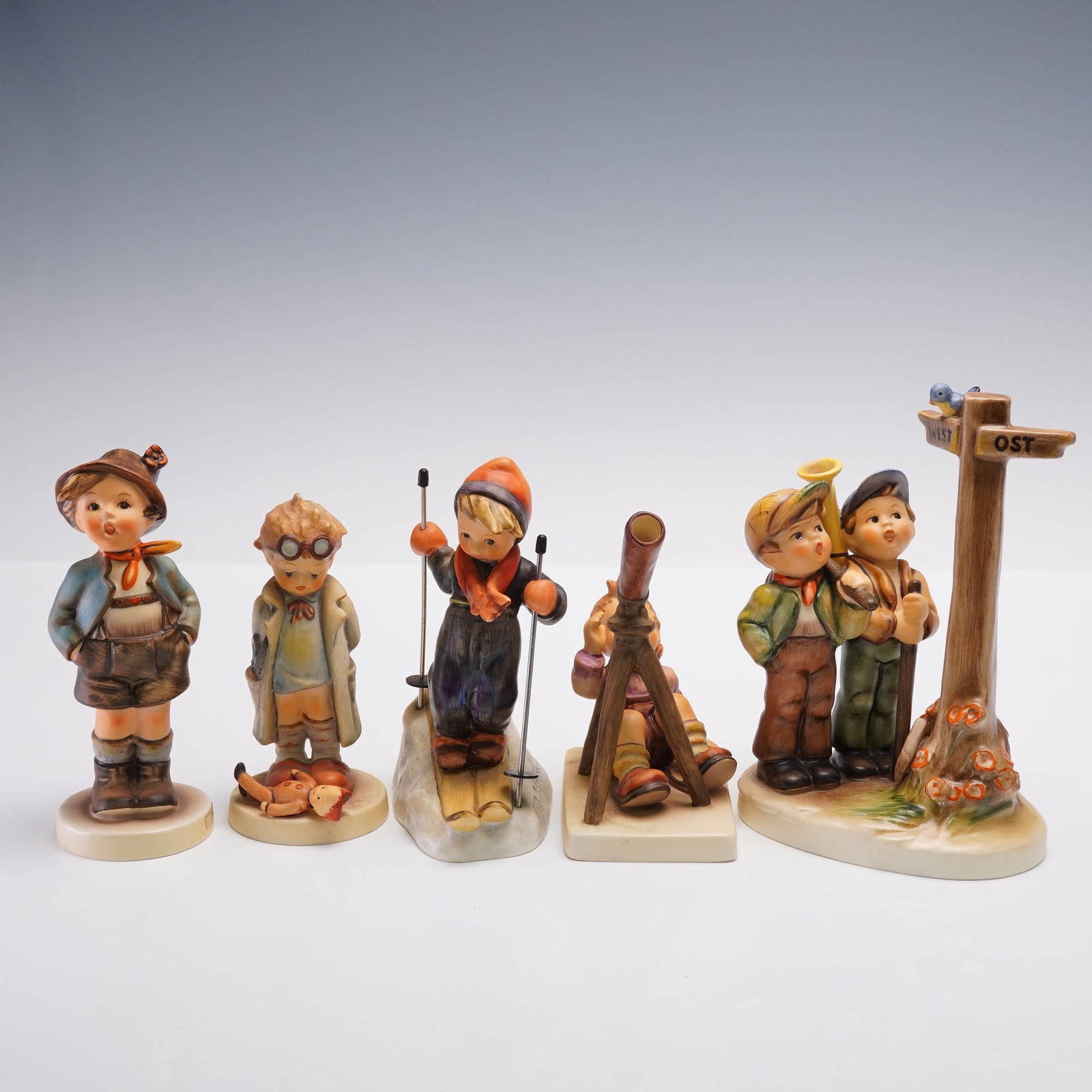 5pc Goebel Hummel Figurines, Outdoor Activities: Group of five Goebel Hummel porcelain figurines, each depicting children in outdoor pursuits. The lot includes: Skier No. 59, a boy on skis with poles; Star Gazer No. 132, a child peering through a te