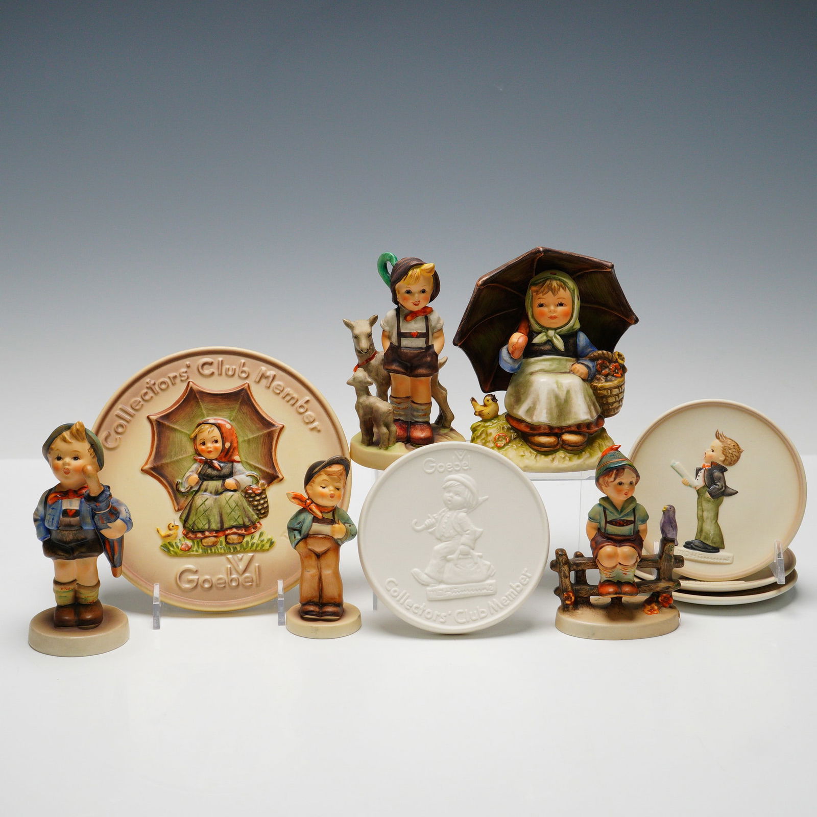 10pc Goebel Hummel Figurines and Plaques: Collection includes five figurines: "Lucky Fellow" (HUM560), "Smiling Through" (HUM408/0), "Wayside Harmony" (HUM111 3/0), "Little Goat Herder" (HUM200-0), and "Market" (HUM198 2/0). Also included are