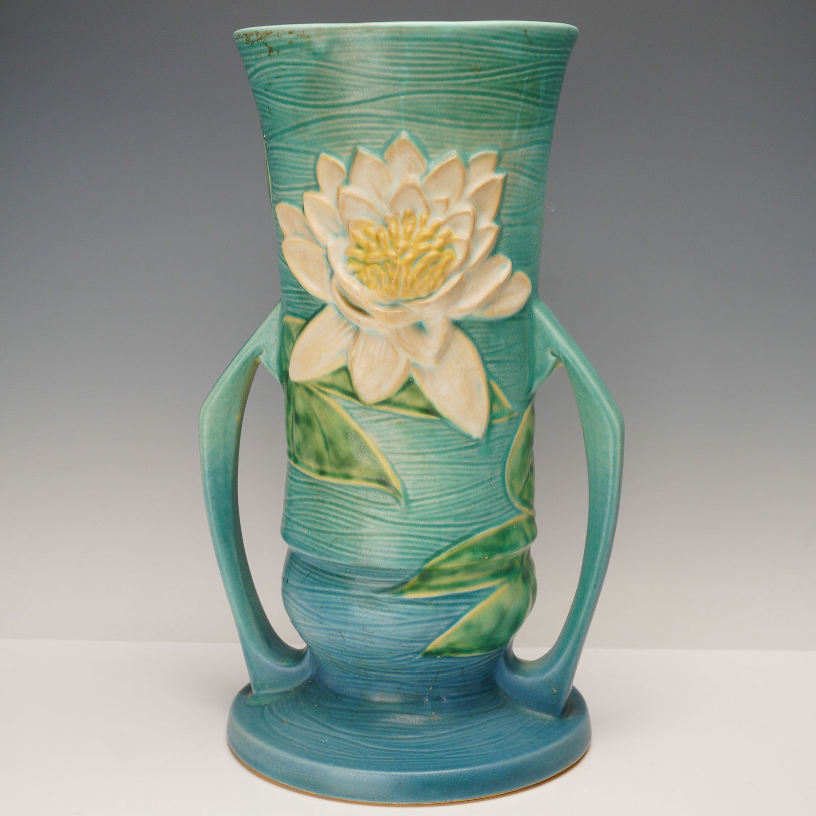 Roseville Pottery Water Lily Floor Vase: A striking Roseville Pottery Water Lily floor vase, shape number 82-14, decorated with a raised motif of creamy white and yellow water lilies with broad green leaves against a turquoise to aqua ground