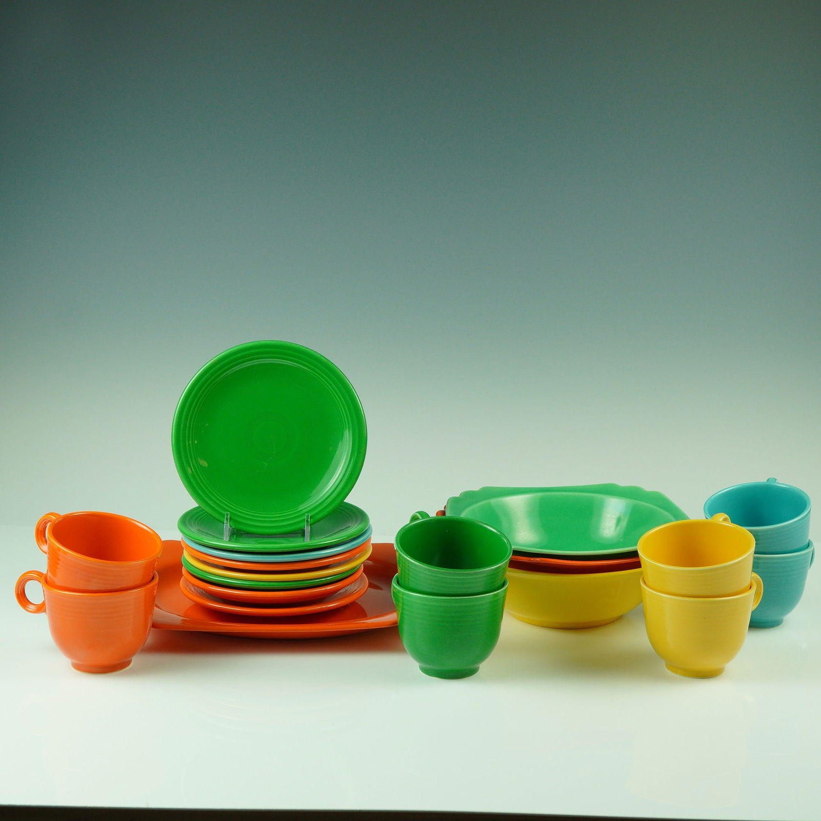 20pc Fiesta Coffee Service with Serving Bowls: A colorful set of vintage Fiesta dinnerware, featuring four scalloped-edge bowls and eight cups with matching saucers, offered in a mix of classic Fiesta hues including orange, green, yellow, and turq