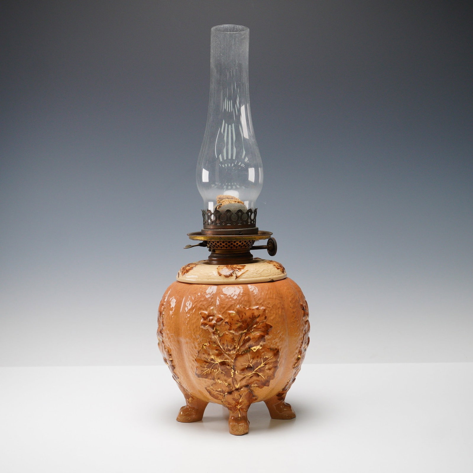 Antique Avalon Bali Majolica Oil Lamp with Floral Relief Decoration: A charming late 19th to early 20th century majolica oil lamp, stamped Avalon Bali to the base. The lamp features a richly glazed earthenware reservoir and matching pedestal base, each decorated in hig