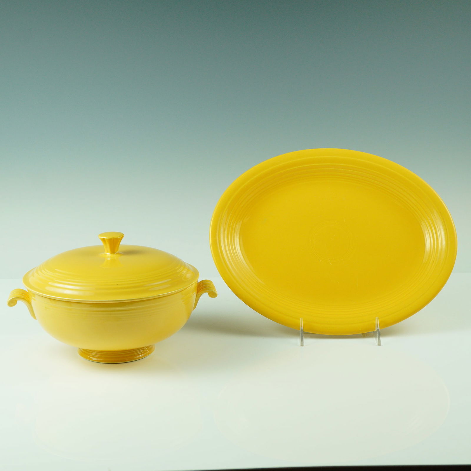 2pc Vintage Fiesta Yellow Serving Pieces, Covered Casserole and Platter: A vibrant pair of vintage Fiesta dinnerware pieces in classic yellow glaze, both marked on the underside "Genuine Fiesta, HLC USA." This set includes a handled covered casserole with matching lid and