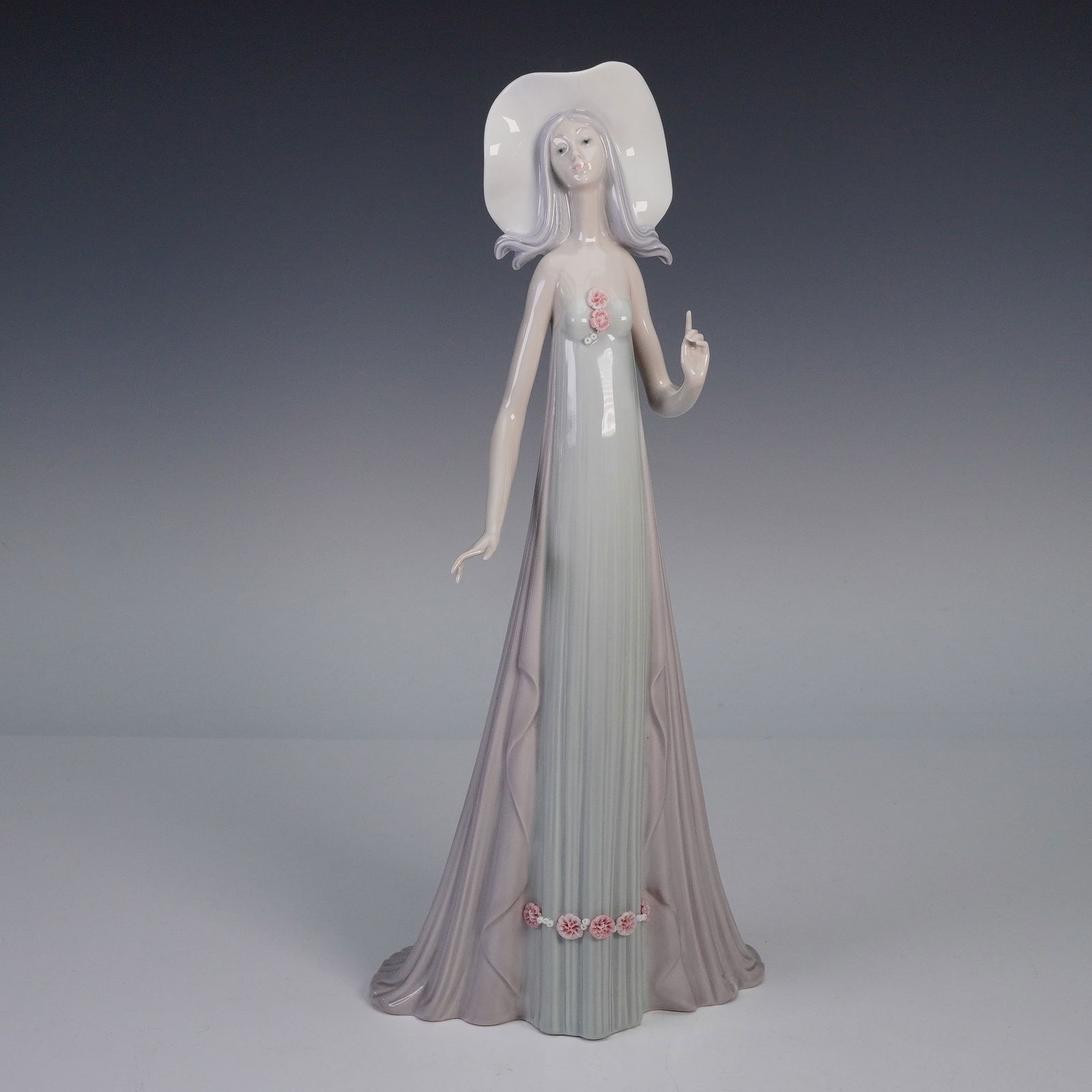 Lladro Porcelain Figurine, The Debutante 1001431 with Original Box: An elegant Lladro porcelain figurine titled The Debutante, model number 1001431. This tall figure portrays a graceful young woman in a flowing pastel gown, adorned with delicate applied flowers and we