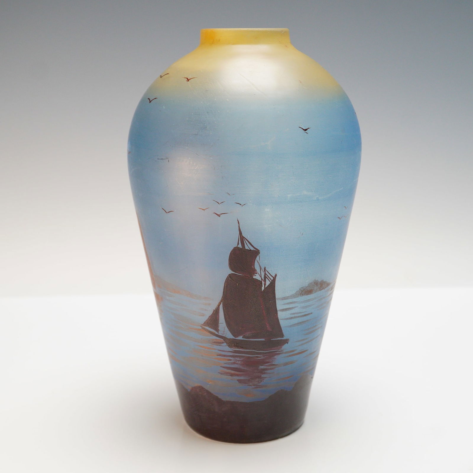 Jean Simon Peynaud Hand Painted Seascape Vase: A striking hand painted vase by French artist Jean Simon Peynaud, signed "Peynaud Bordeaux." The vase presents a detailed maritime scene with a sailboat on calm waters beneath a sky filled with flying
