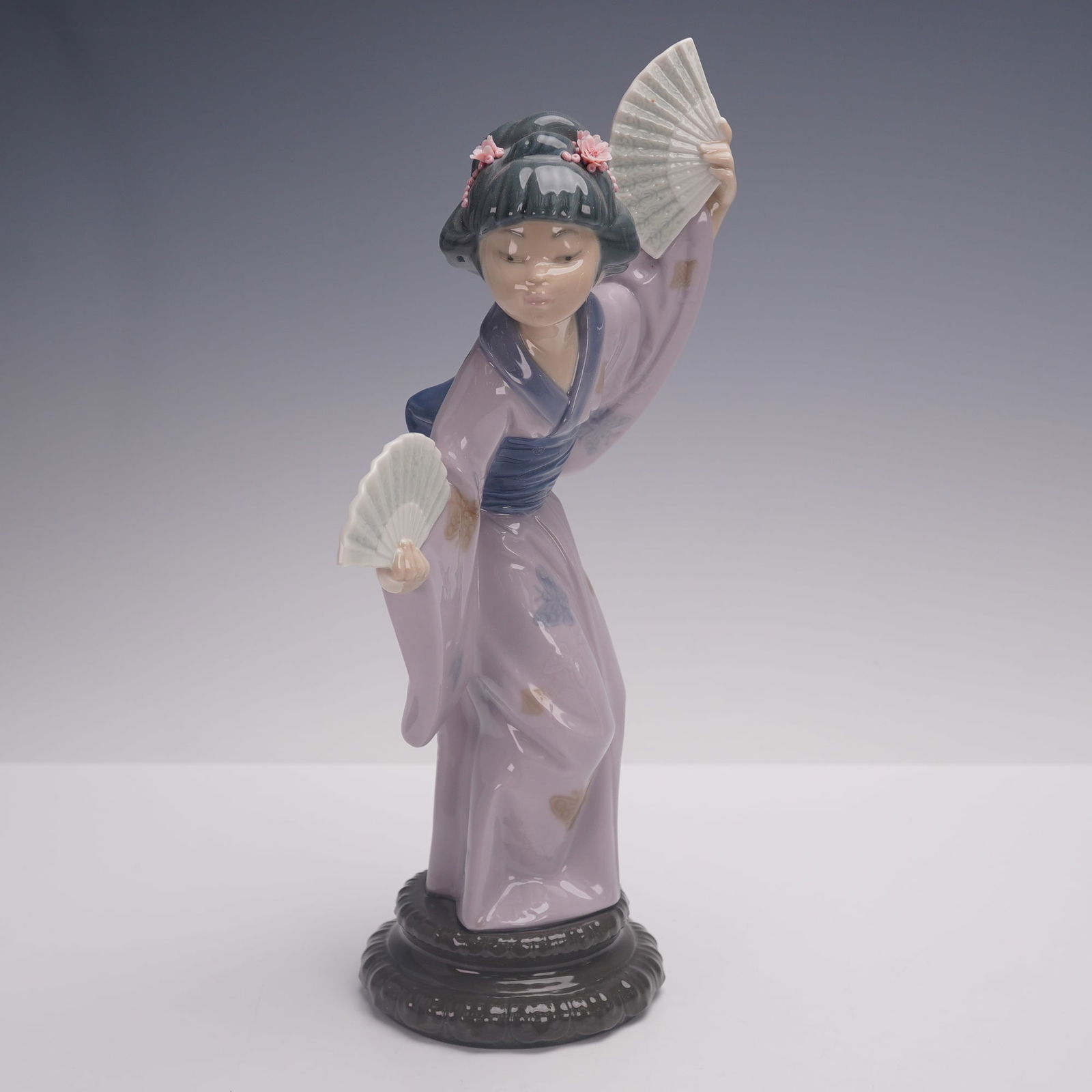 Lladro Porcelain Figurine, Madame Butterfly 1004991: A Lladro porcelain figurine titled Madame Butterfly, number 1004991, depicting a graceful woman in a lilac kimono with floral and butterfly motifs, holding two fans while posed in an elegant dance. Fi