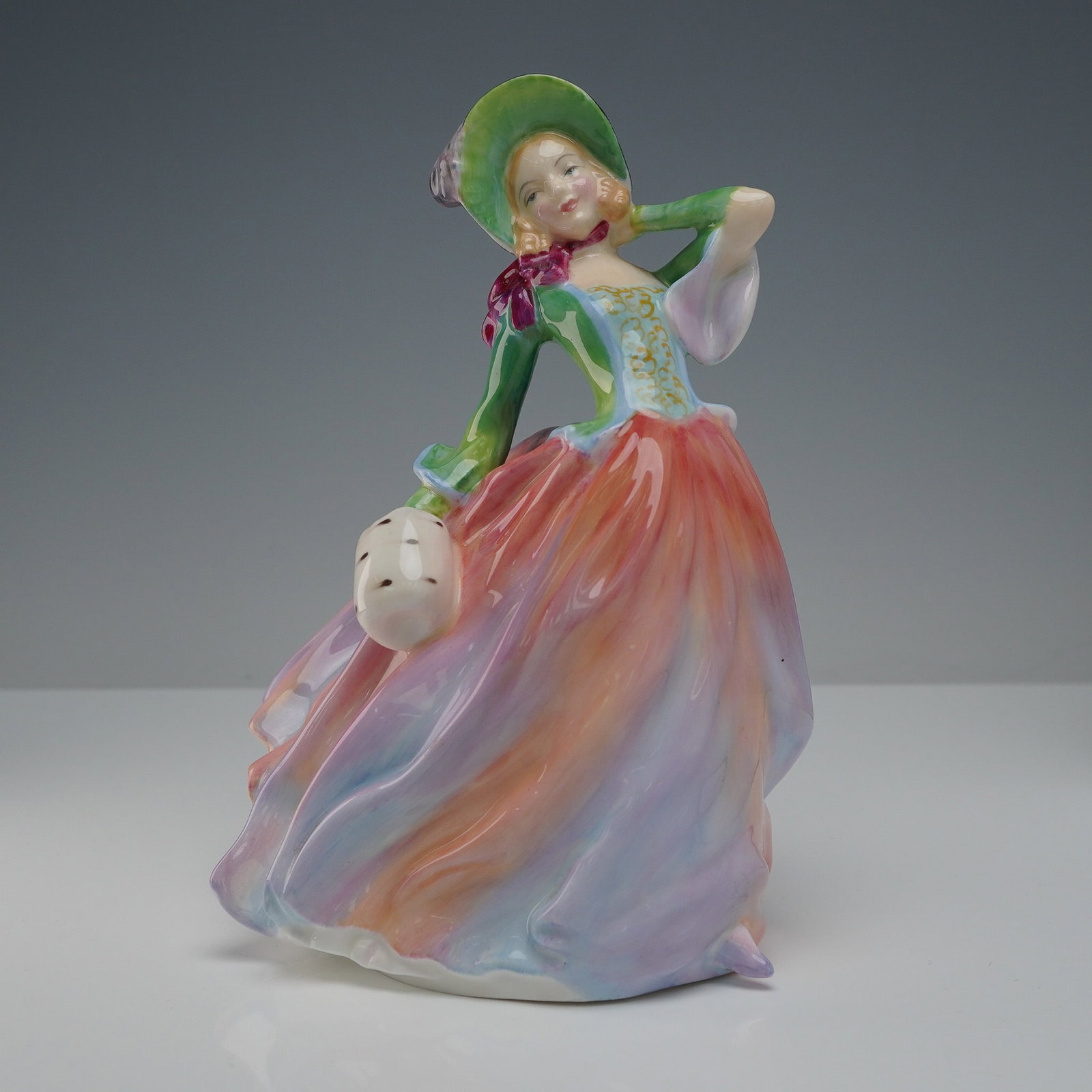 Royal Doulton Figurine, Autumn Breezes HN 1911: A graceful Royal Doulton porcelain figurine titled Autumn Breezes, model HN 1911, designed by Leslie Harradine. Issued between 1939 and 1976, this piece portrays a young woman in a flowing dress of or
