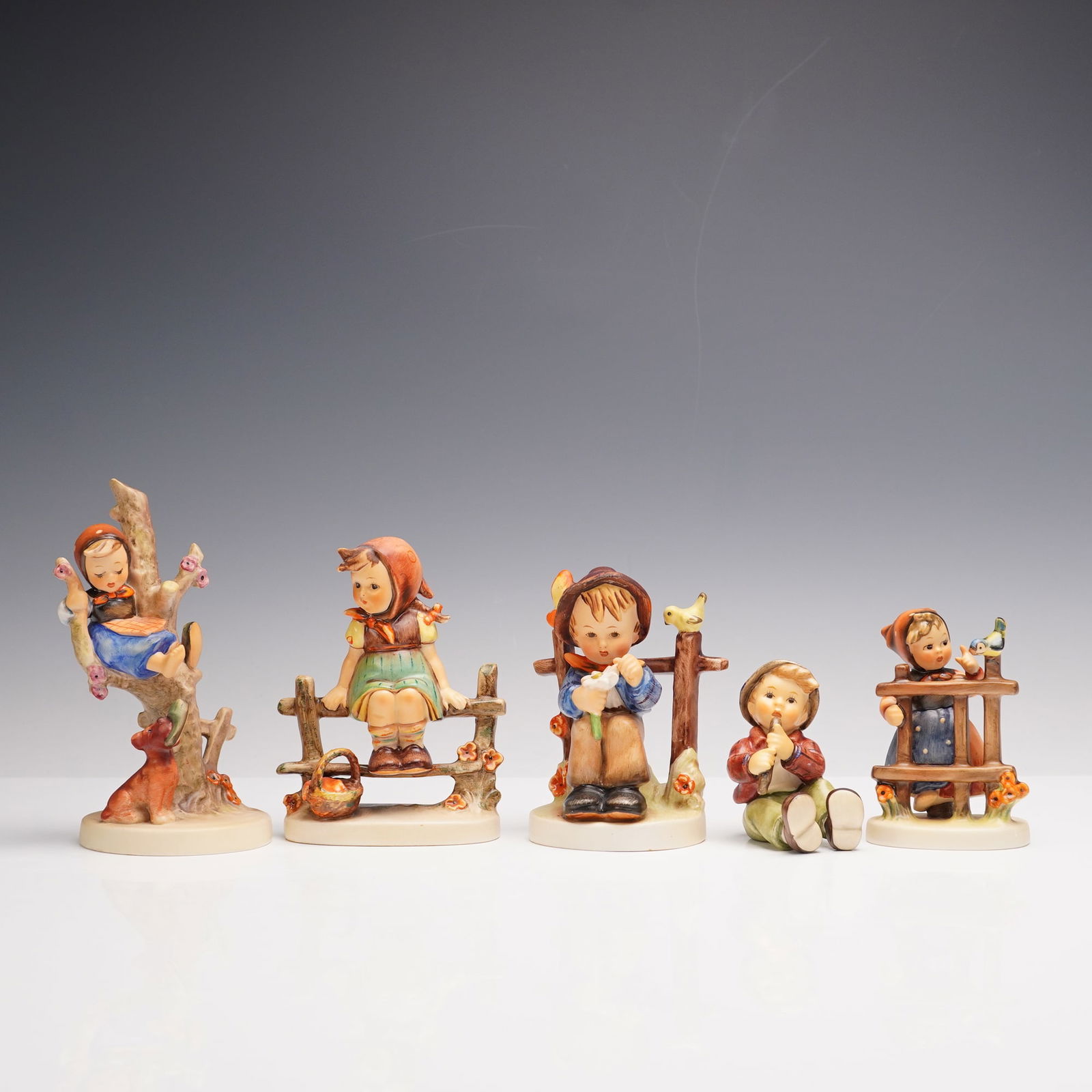 5pc Goebel Hummel Figurines: Charming group of five Hummel figurines including Out of Danger with a girl perched in a tree as a playful dog holds her shoe below, Signs of Spring with a girl leaning at a fence beside a small bird,