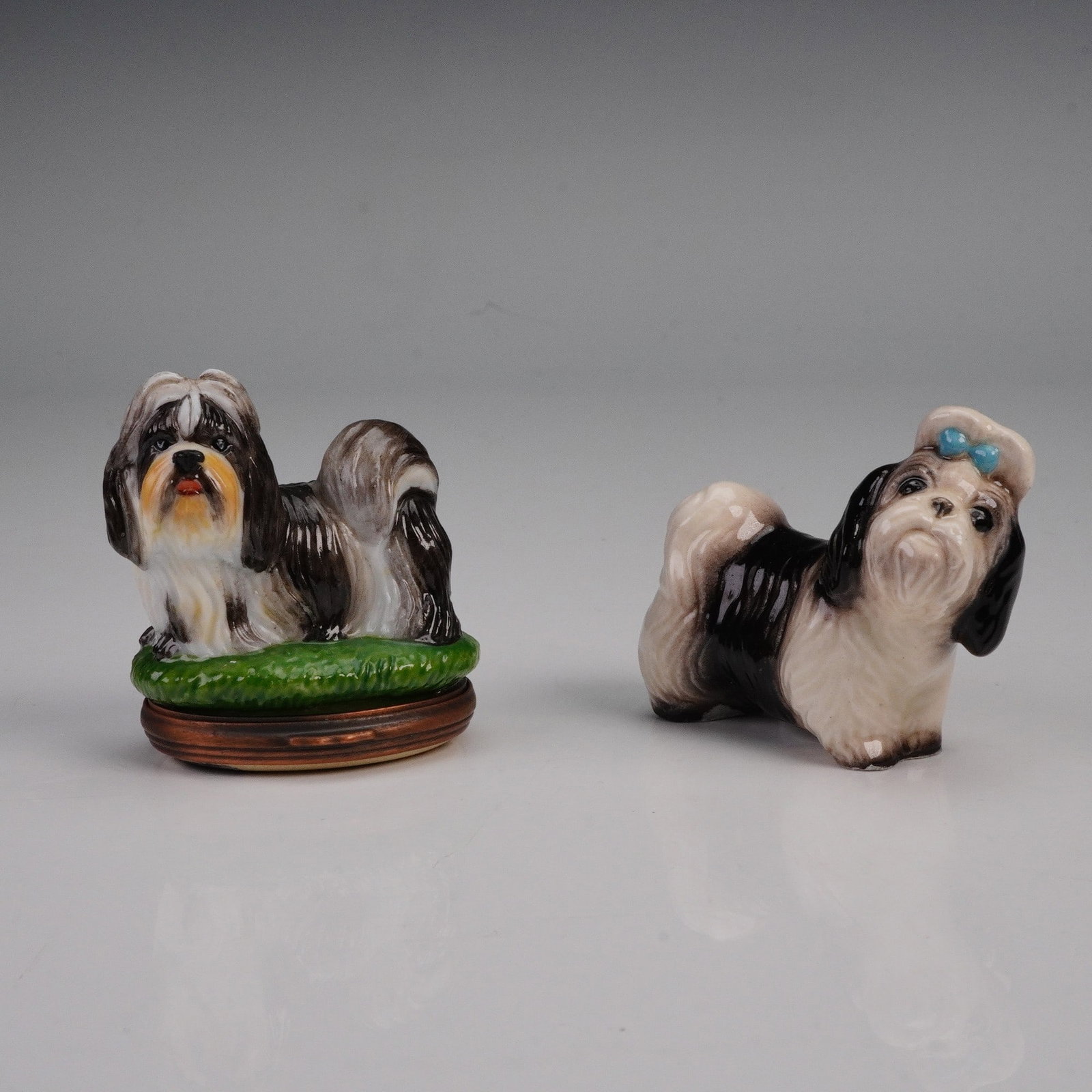 2pc Halcyon Days and Hagen Renaker Shih Tzu Figurine and Trinket Box: A charming two-piece Shih Tzu collectibles. The first is a Halcyon Days enamel trinket box in the form of a Shih Tzu standing on grass, with a hinged opening that reveals a painted dog bowl and bone i