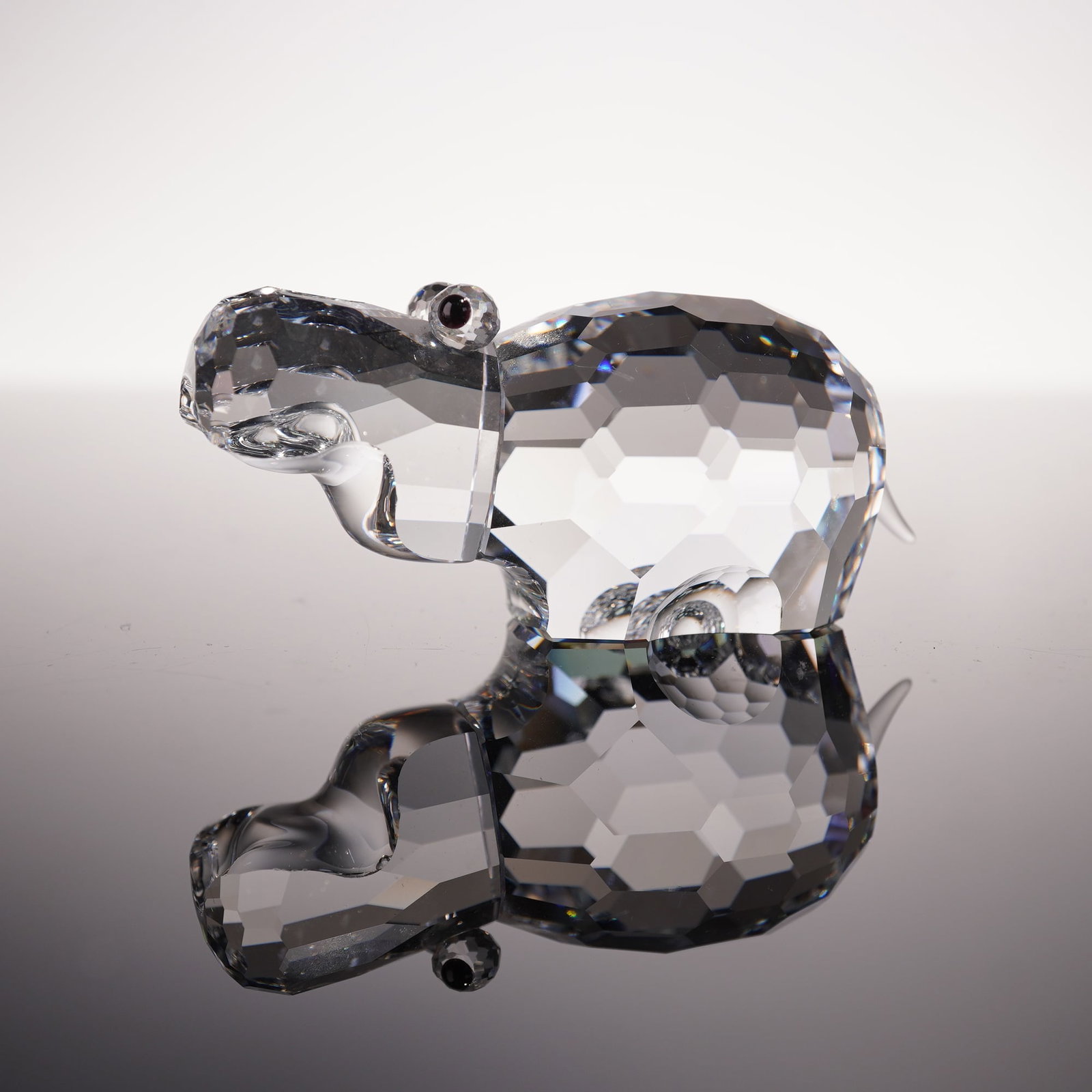 Swarovski Crystal Figurine, Large Hippopotamus: Swarovski crystal figurine of a large hippopotamus, designed by Adi Stocker. This endearing piece captures the hippo's rounded form with a fully faceted clear crystal body, accented with small black c