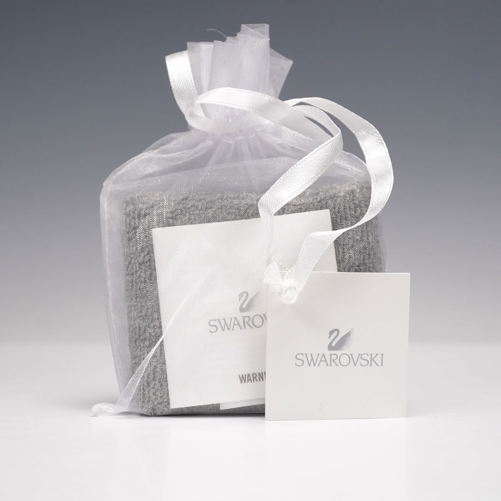 Swarovski Event Gift Wristband: This soft gray wristband is accented with Swarovski crystals forming the brands signature swan motif. Presented in its original organza pouch with Swarovski tag, this piece was created as an exclusive