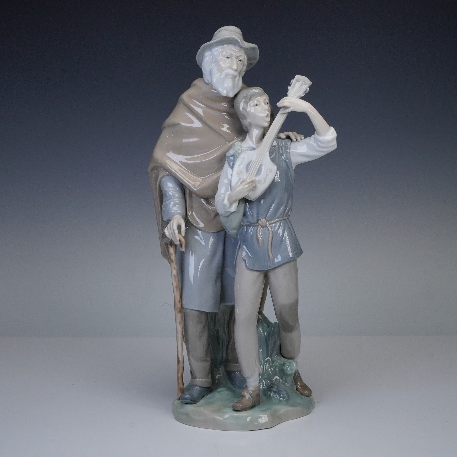 Lladro Porcelain Figurine, Happy Travelers 01004652: Lladro porcelain figurine titled Happy Travelers (model 01004652), designed by Salvador Furio and first issued in 1970. The scene depicts an elderly traveler with a walking stick standing beside a you