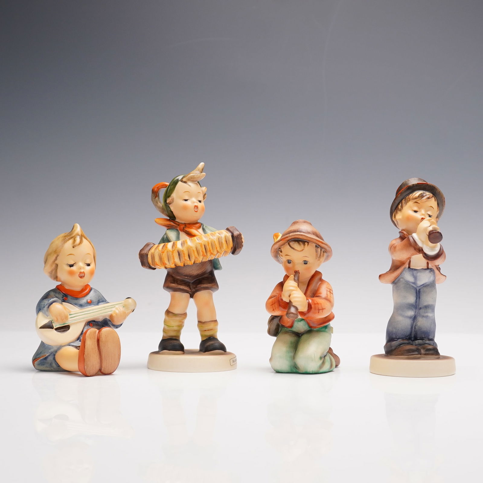 4pc Goebel Hummel Figurines, Making Music: Delightful grouping of four Goebel Hummel figurines, each celebrating the joy of music. Includes Serenade 85/0, depicting a seated child strumming a mandolin; Little Tooter, a young boy earnestly blow
