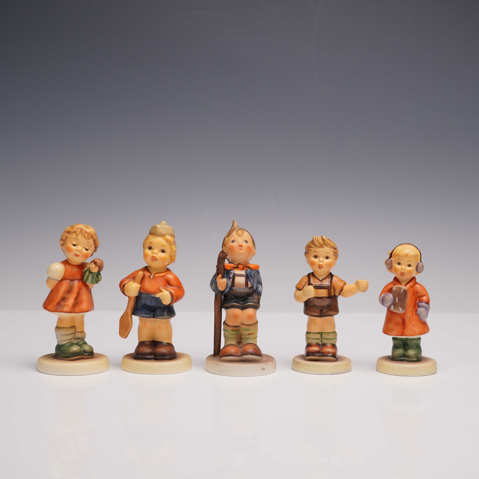 5pc Goebel Hummel Porcelain Figurines: Charismatic collection of five hand painted delicate figurines depicting children in various poses. Includes Sweet Freedom, Puppet Princess, First Mate, Little Hiker, and Pledge to America. These deta