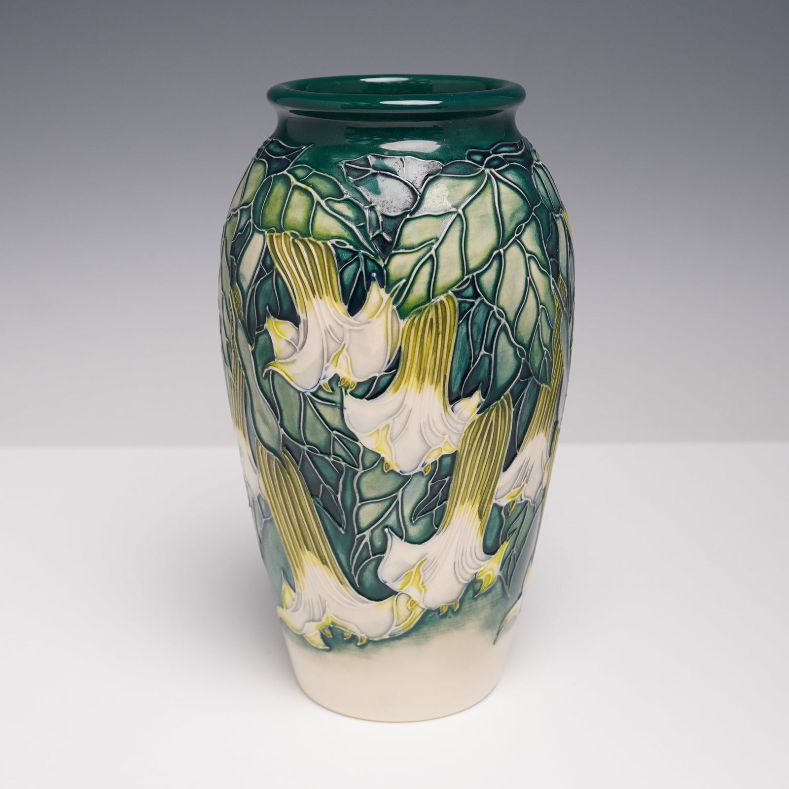 Moorcroft Pottery Vase by Angie Davenport, Angel's Trumpet: A fine Moorcroft pottery vase decorated in the Angel's Trumpet pattern by designer Angie Davenport. The tall baluster form is richly adorned with cascading white and yellow Angel's Trumpet blooms agai