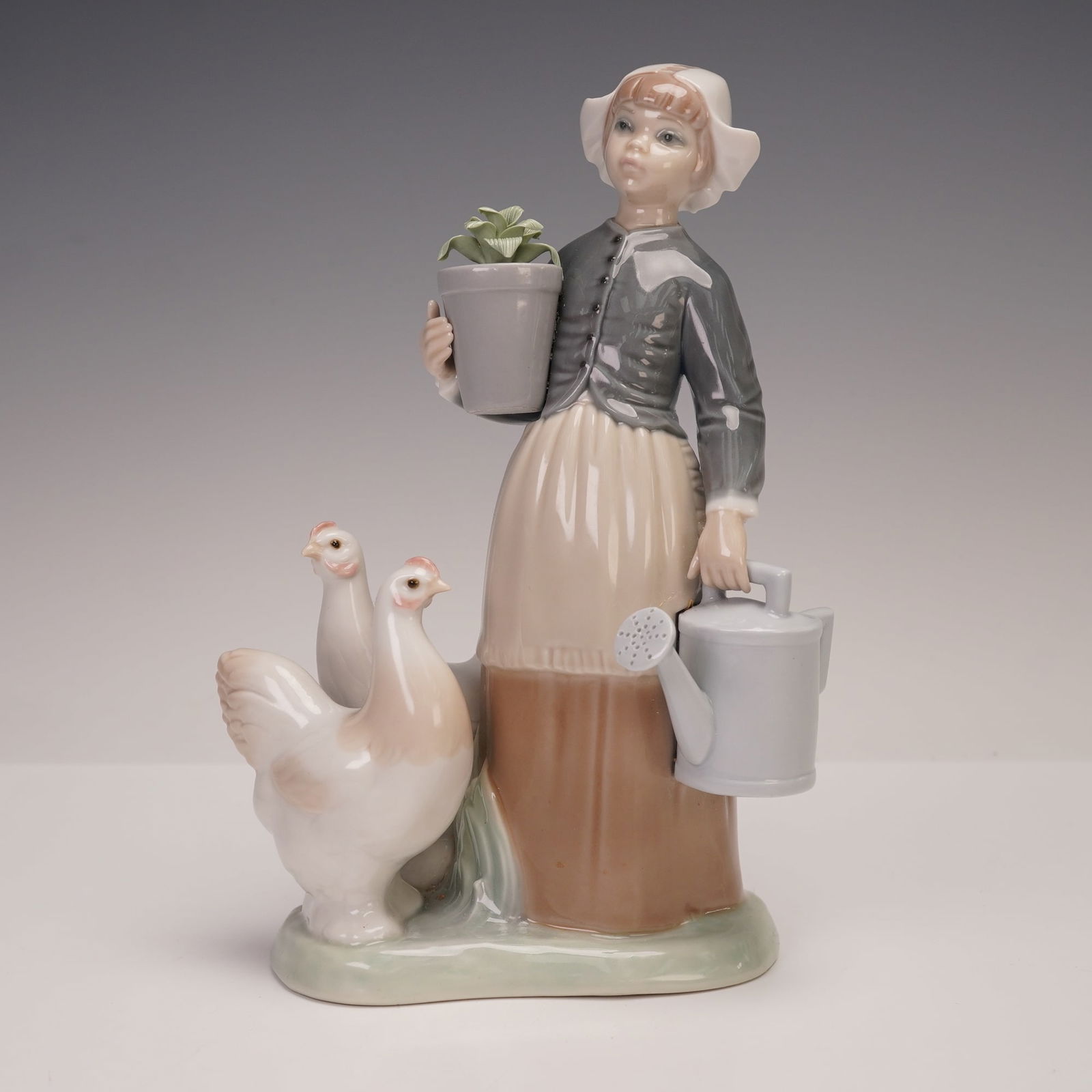 Lladro Vintage Figurine, Girl with Hens 1001103: A porcelain figurine depicting a young girl in traditional attire holding a watering can in one hand and a potted plant in the other, accompanied by two hens at her side. Executed in Lladro's signatur
