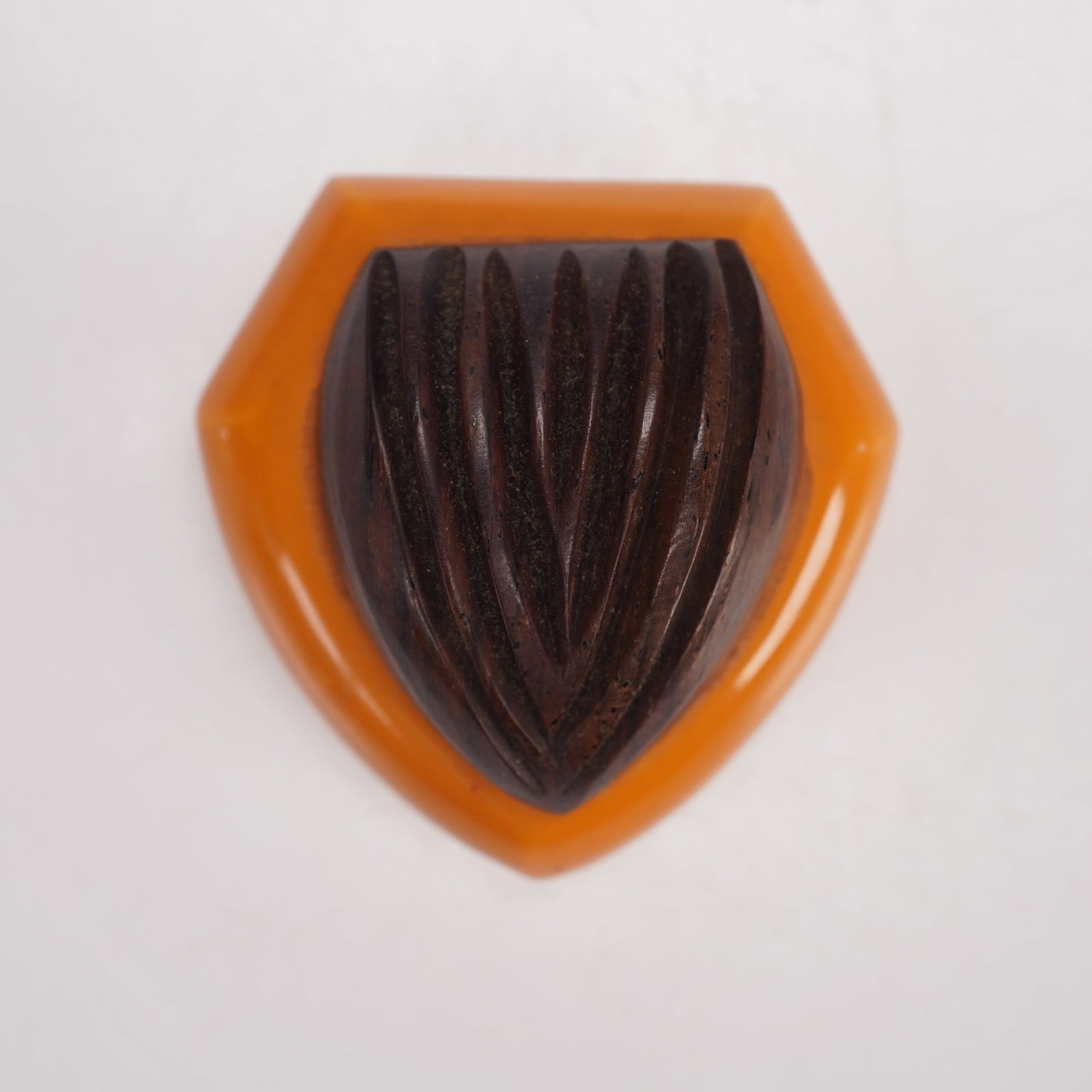 Bakelite and Carved Wood Dress Clip: This 1930s Art Deco dress clip is fashioned from two contrasting materials, combining a butterscotch Bakelite panel with a carved dark wood element fitted together in a shield form. The reverse is equ