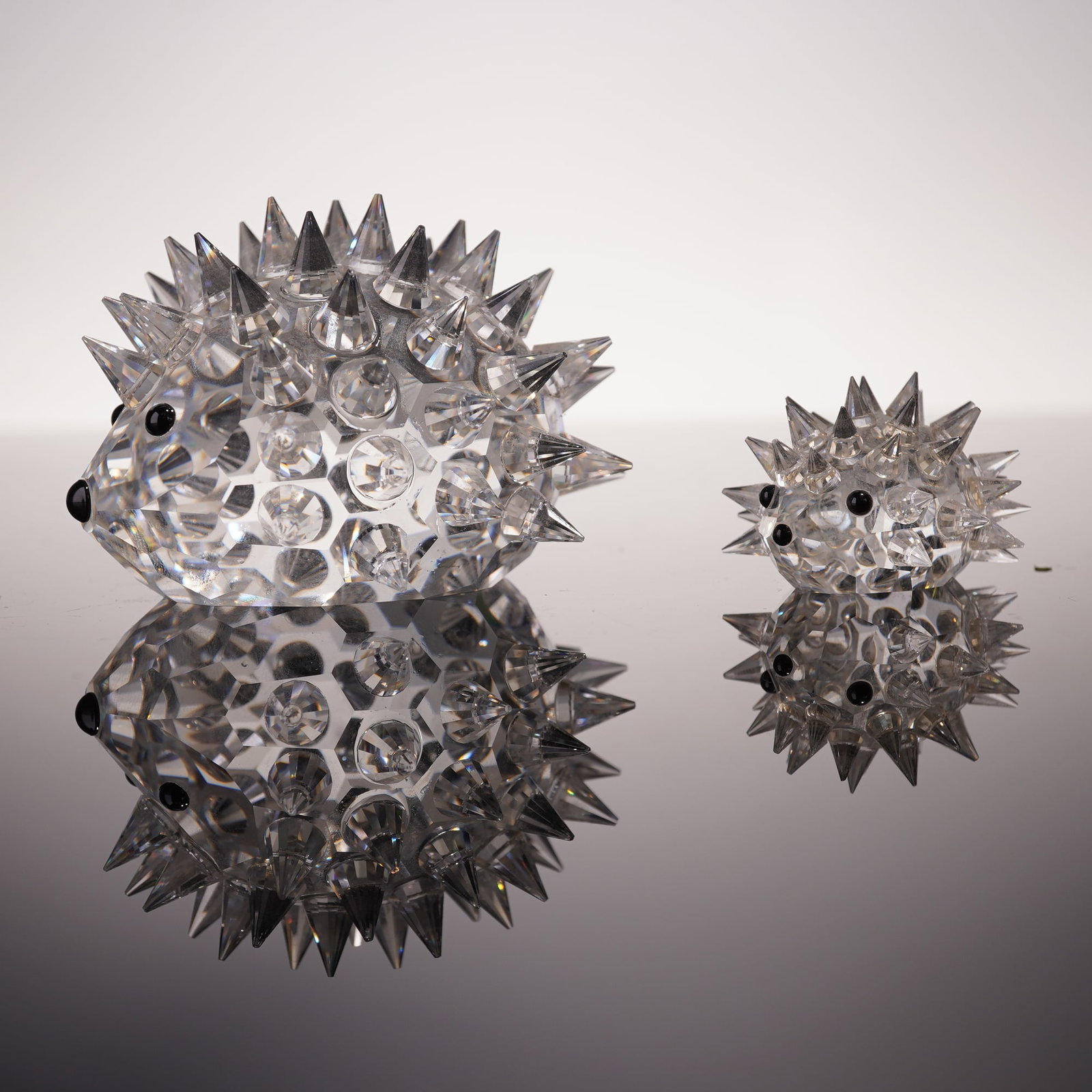 2pc Swarovski Crystal Figurines, Large and Small Oval Hedgehog: Swarovski crystal hedgehog figurines designed by Max Schreck, including both the large and small oval versions. Each features a faceted clear crystal body with pointed crystal spines and expressive bl